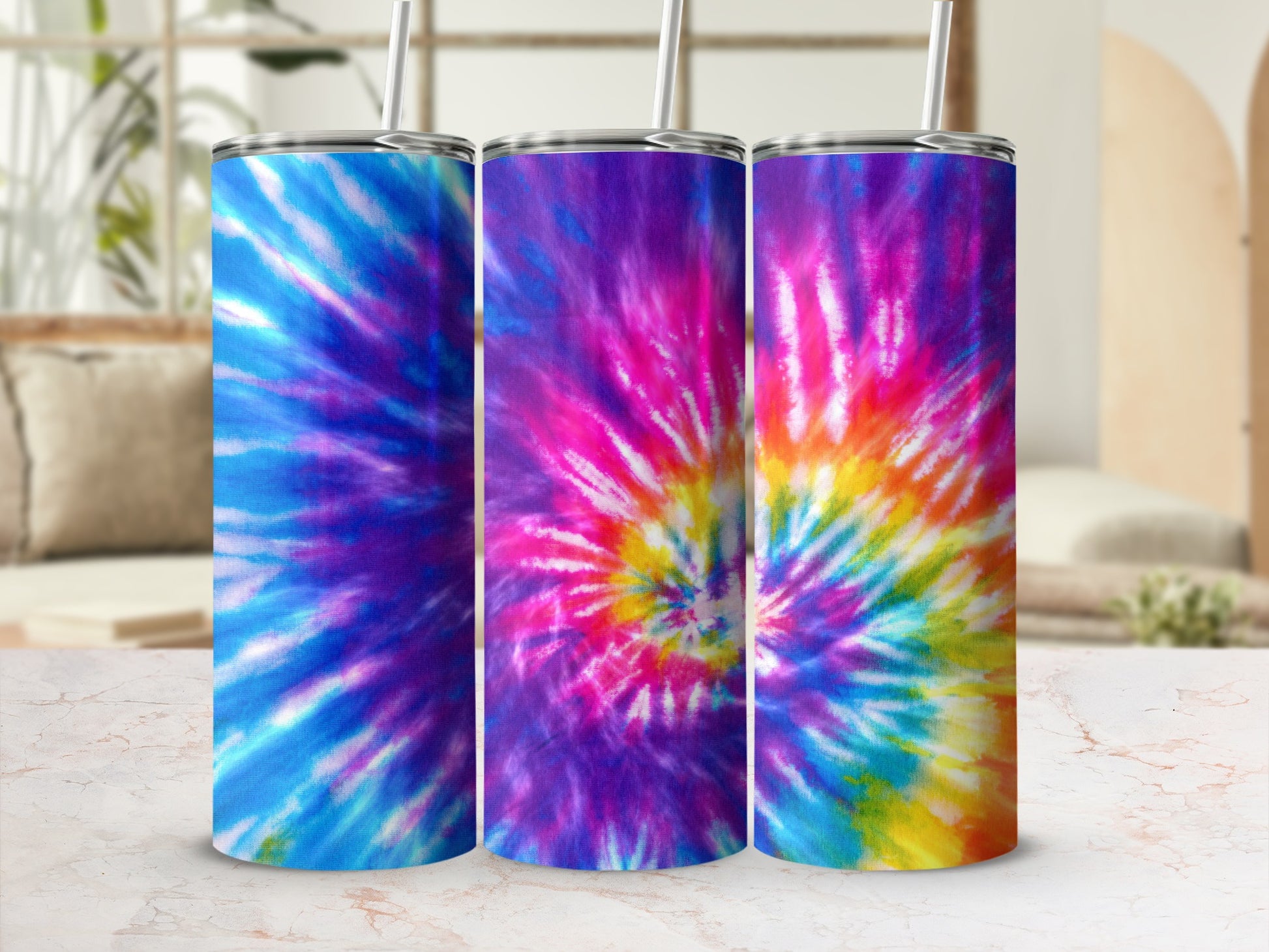 Three tumblers with vibrant tie-dye patterns displayed on a marble surface.
