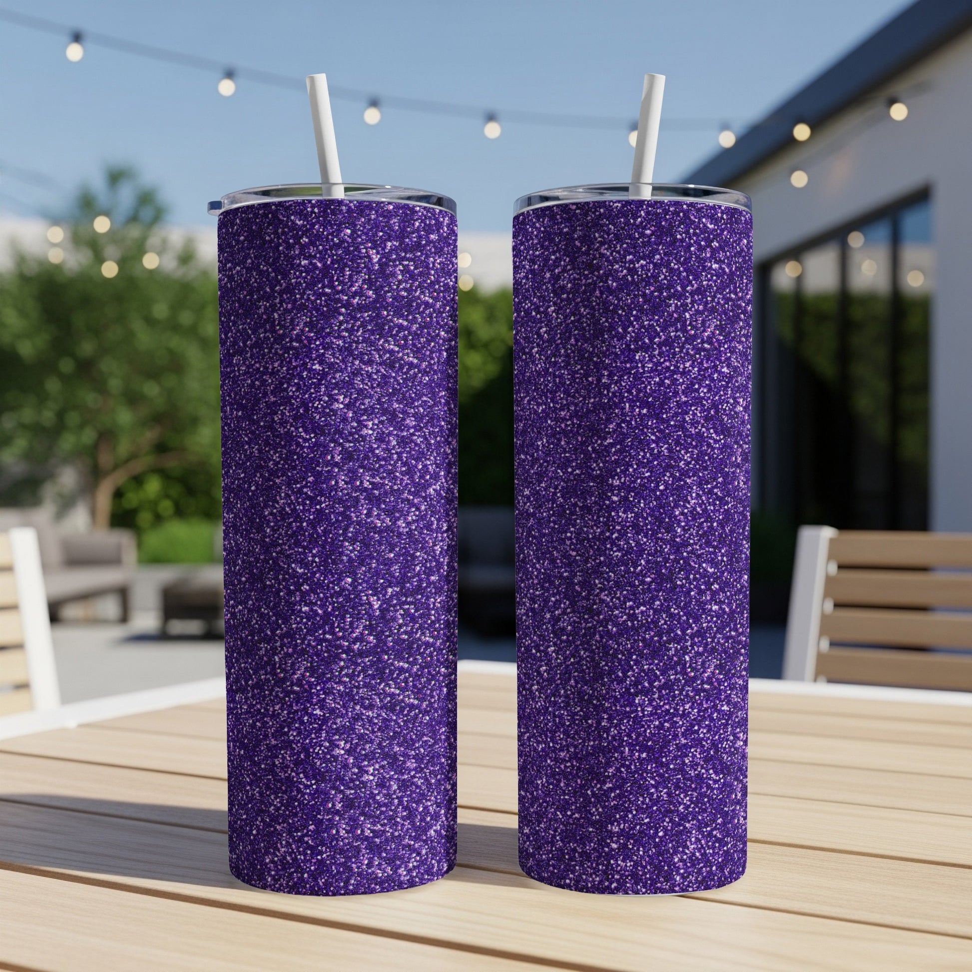Two purple glitter tumblers with white straws on a wooden table.