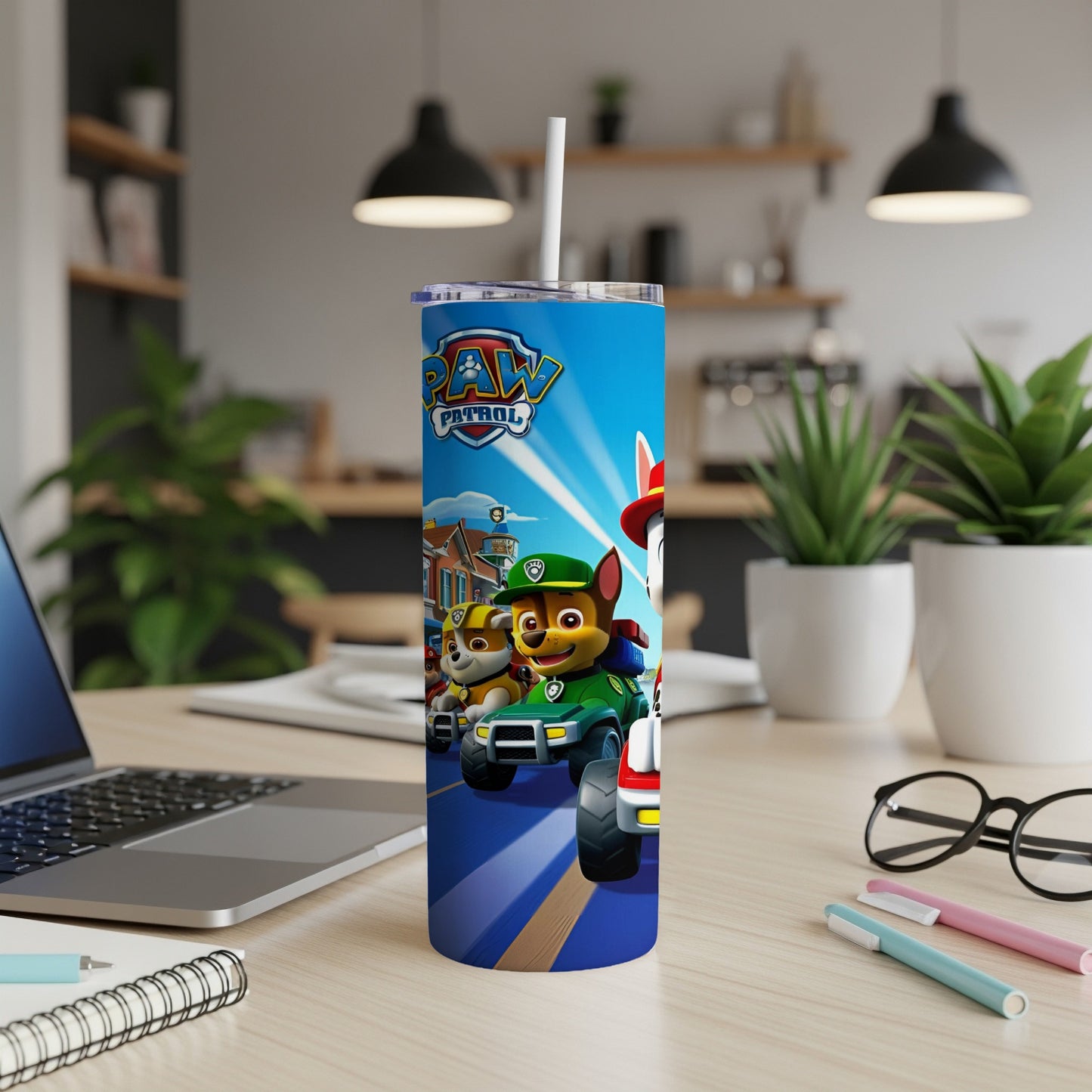 Paw Patrol characters on a blue tumbler with a straw, on a desk.