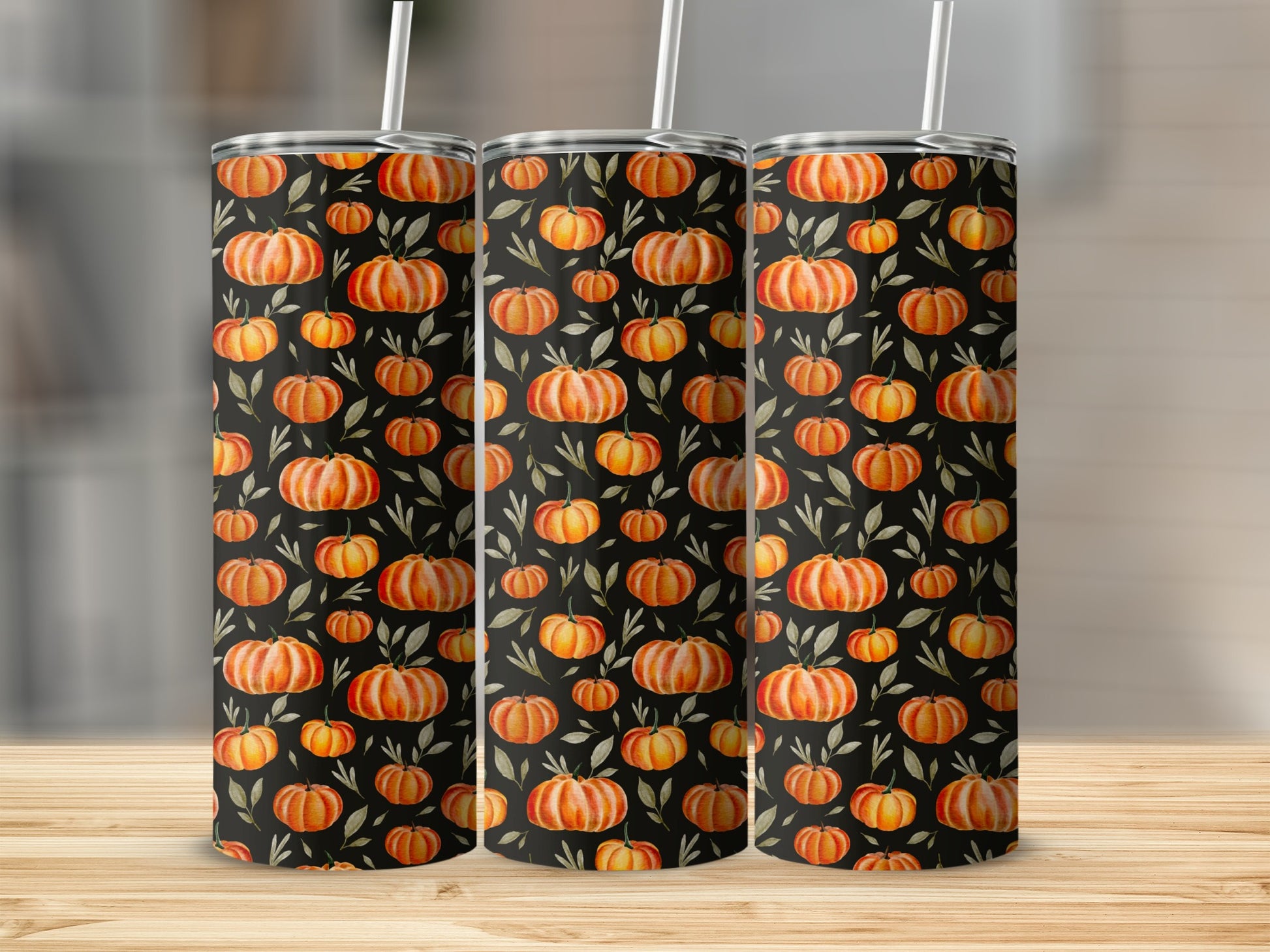 Three tumblers with orange pumpkins and green leaves pattern on black background.