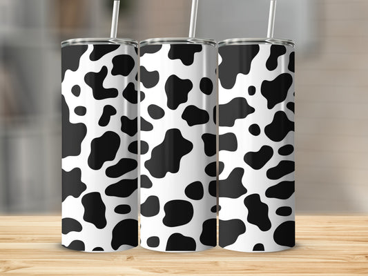 Three tumblers with black and white cow print pattern, standing on a wooden surface.