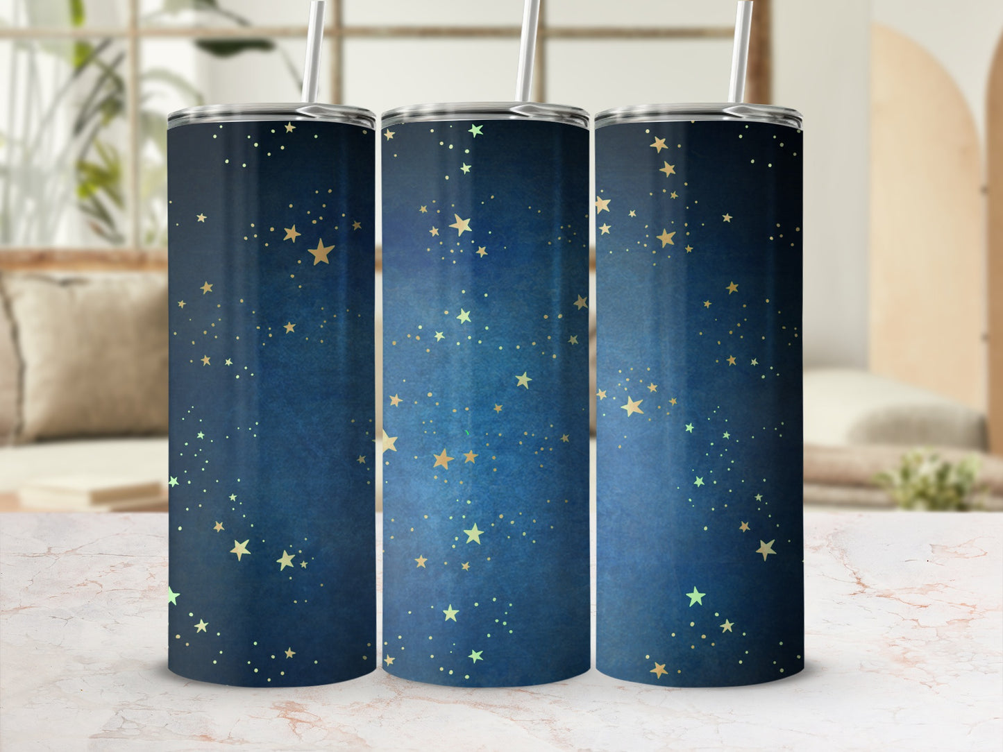 Three tumblers with a dark blue starry night design and silver straws.