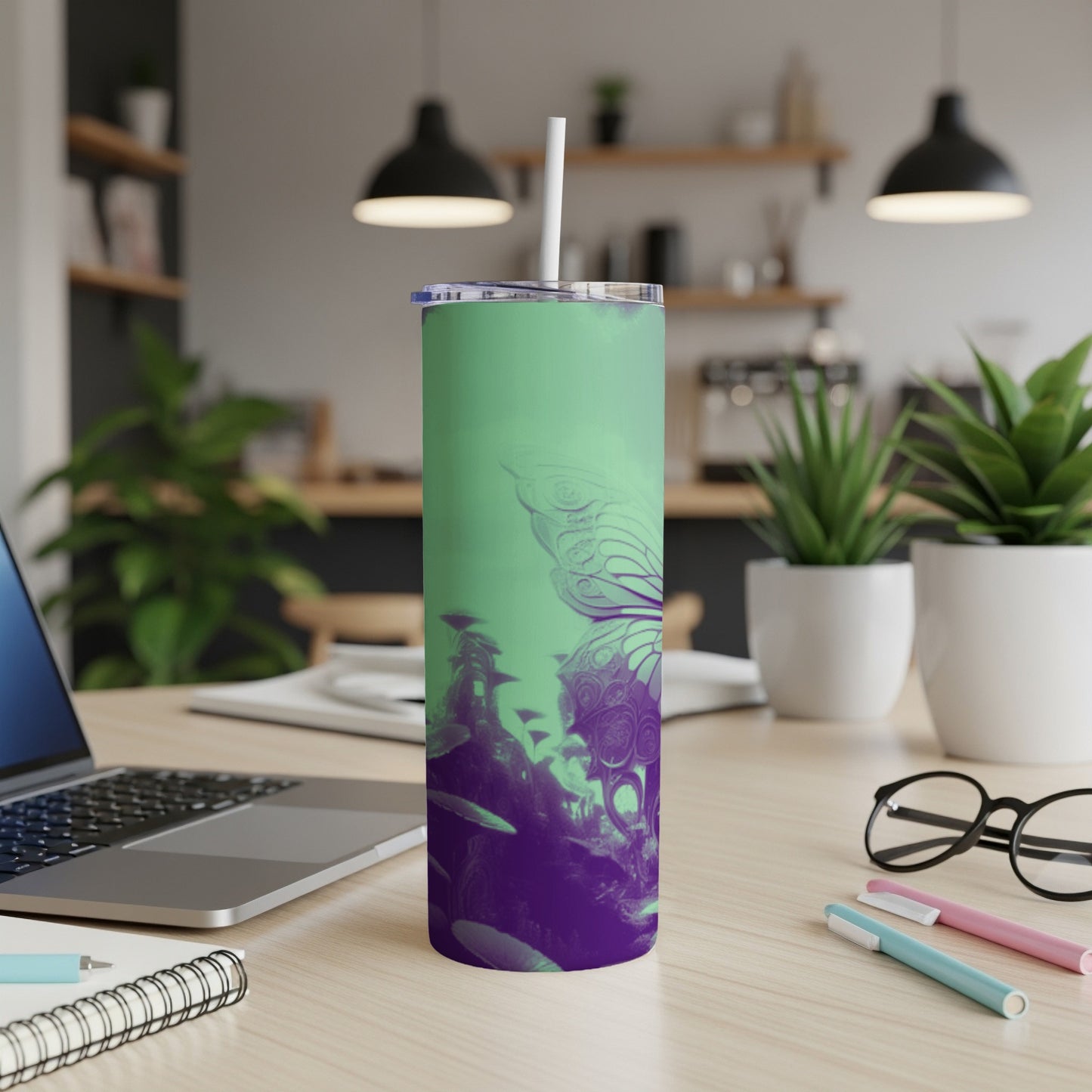 Green and purple butterfly tumbler with straw on desk.