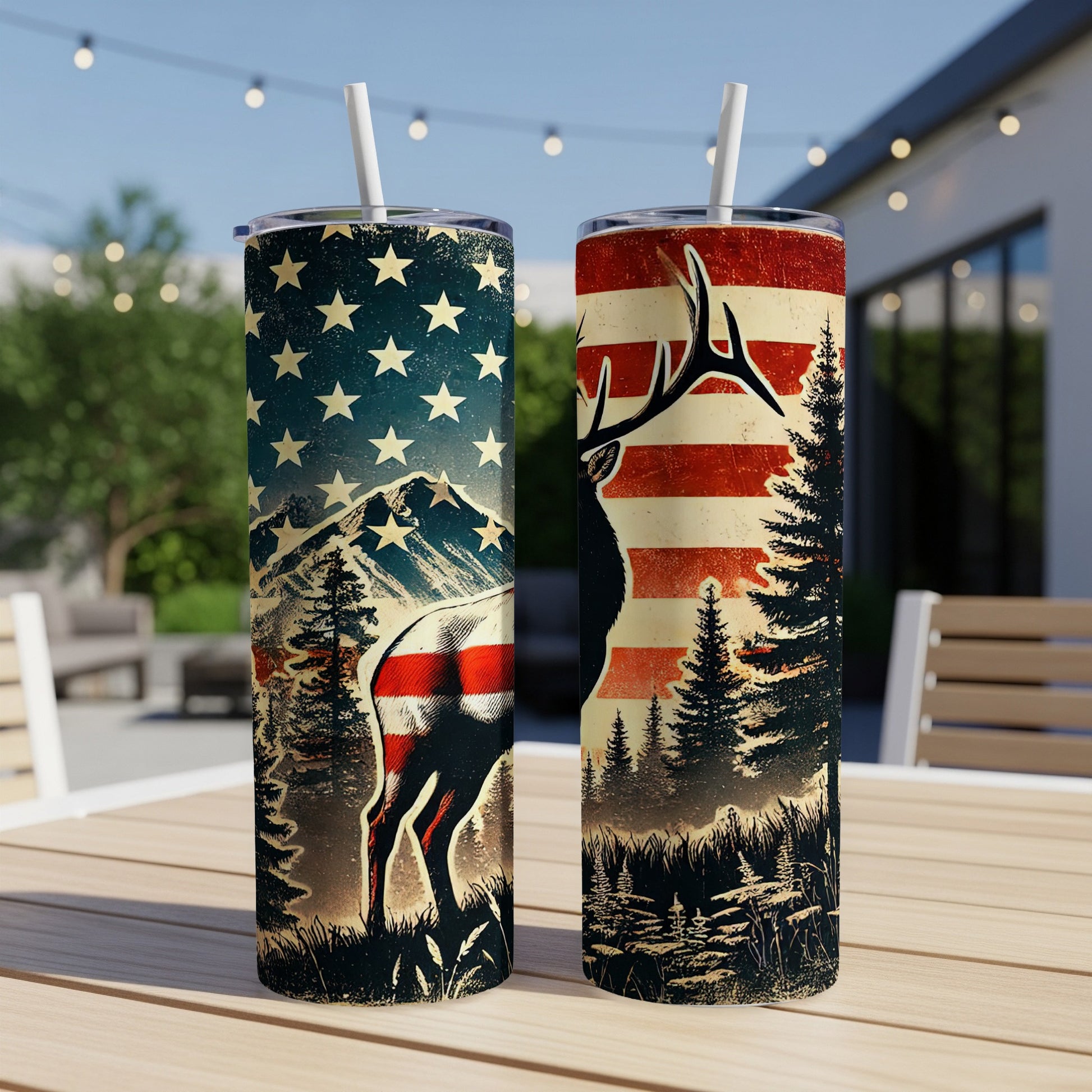Two patriotic tumblers with deer and mountains, on a table outdoors.