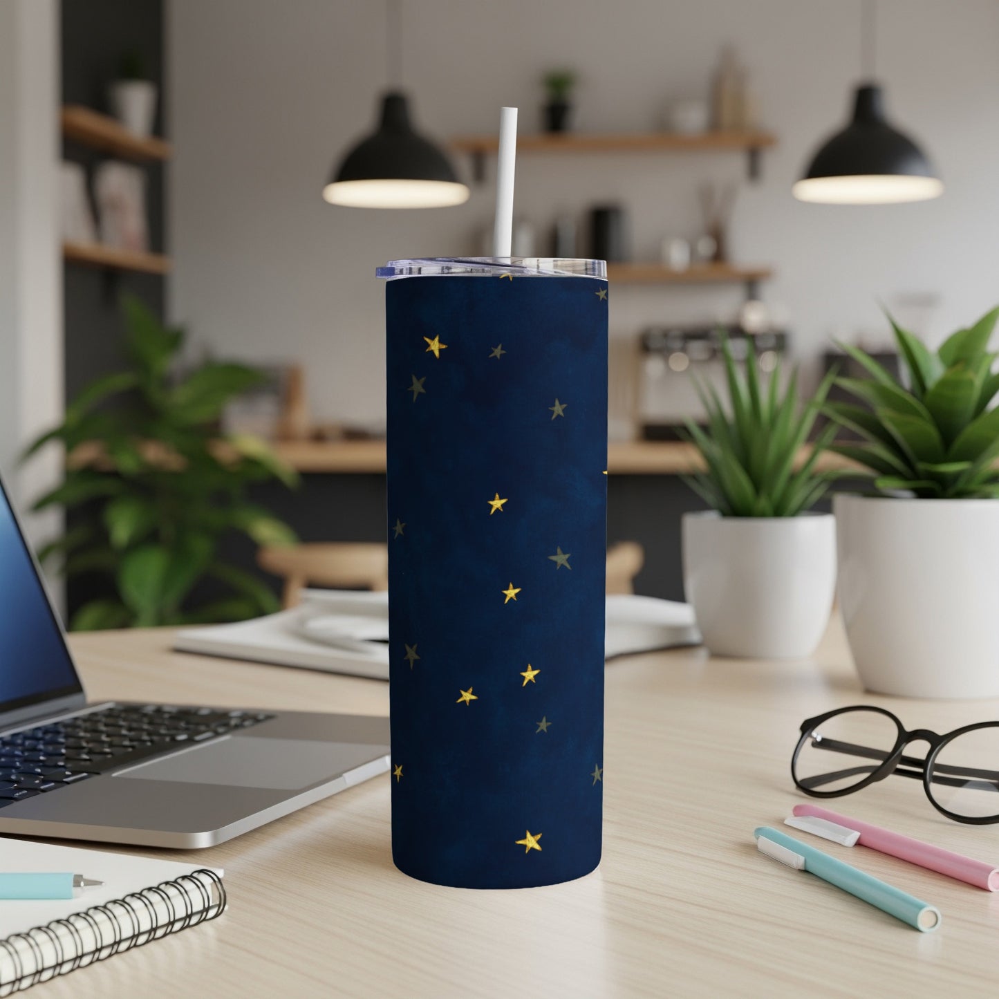 Dark blue tumbler with gold stars and white straw on a desk.