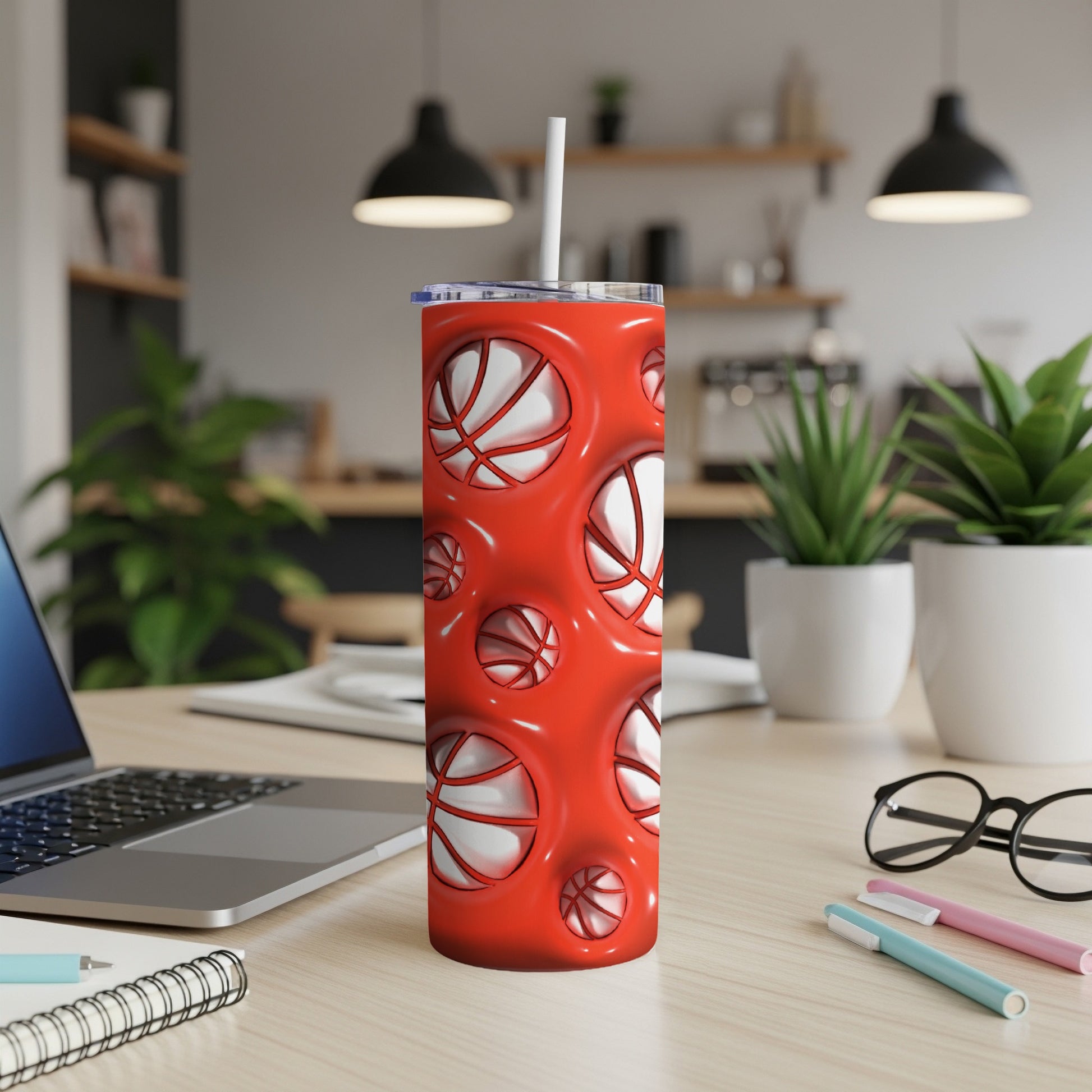 Red tumbler with basketball pattern and white straw on a desk.