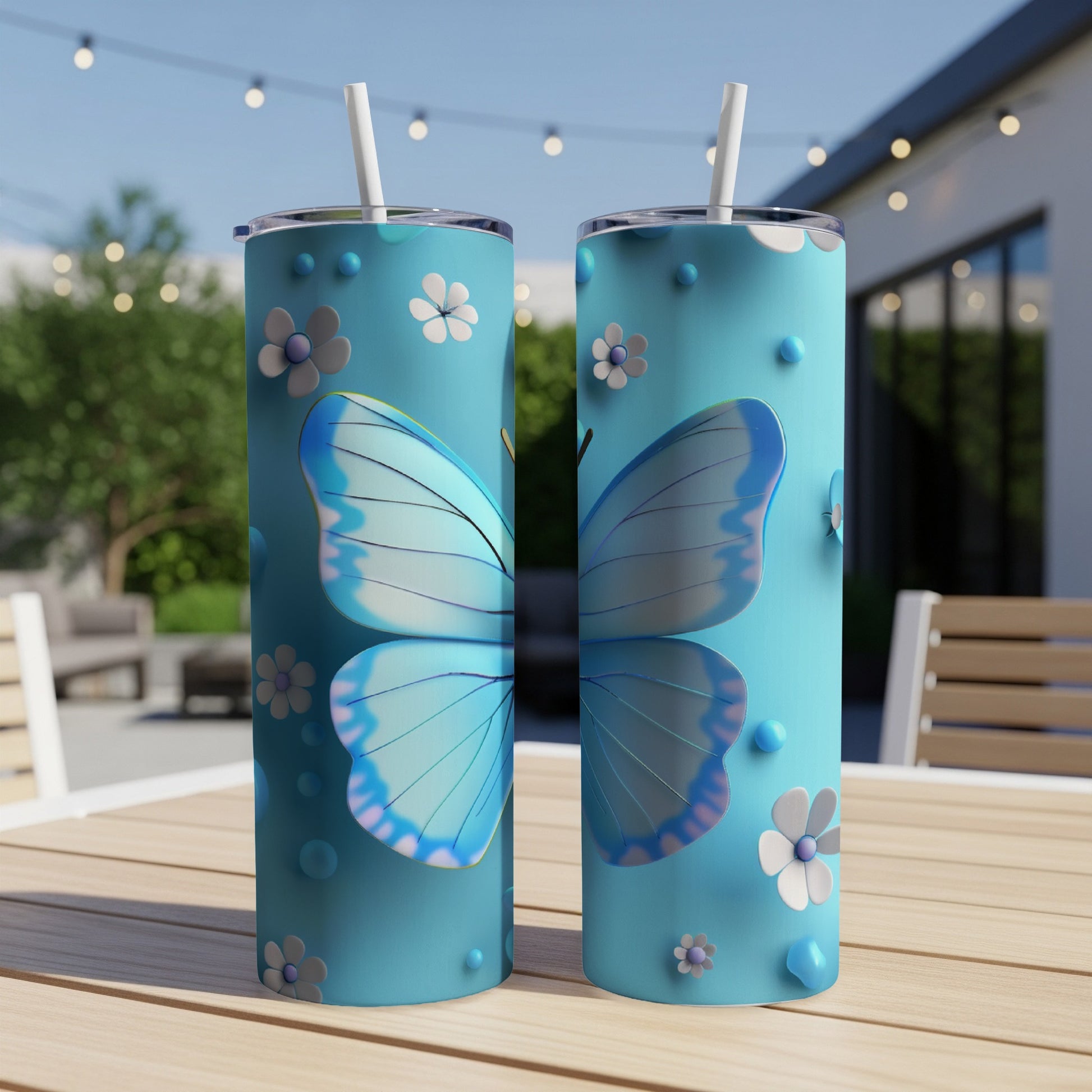 Two blue tumblers with butterfly and flower designs sit on a table.