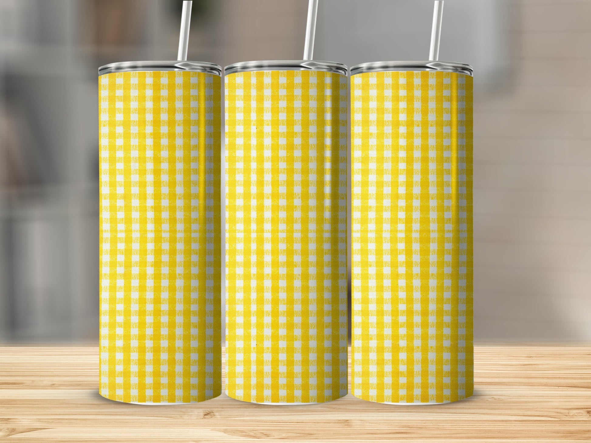 Three tumblers with a yellow and white gingham pattern stand on a wooden surface.