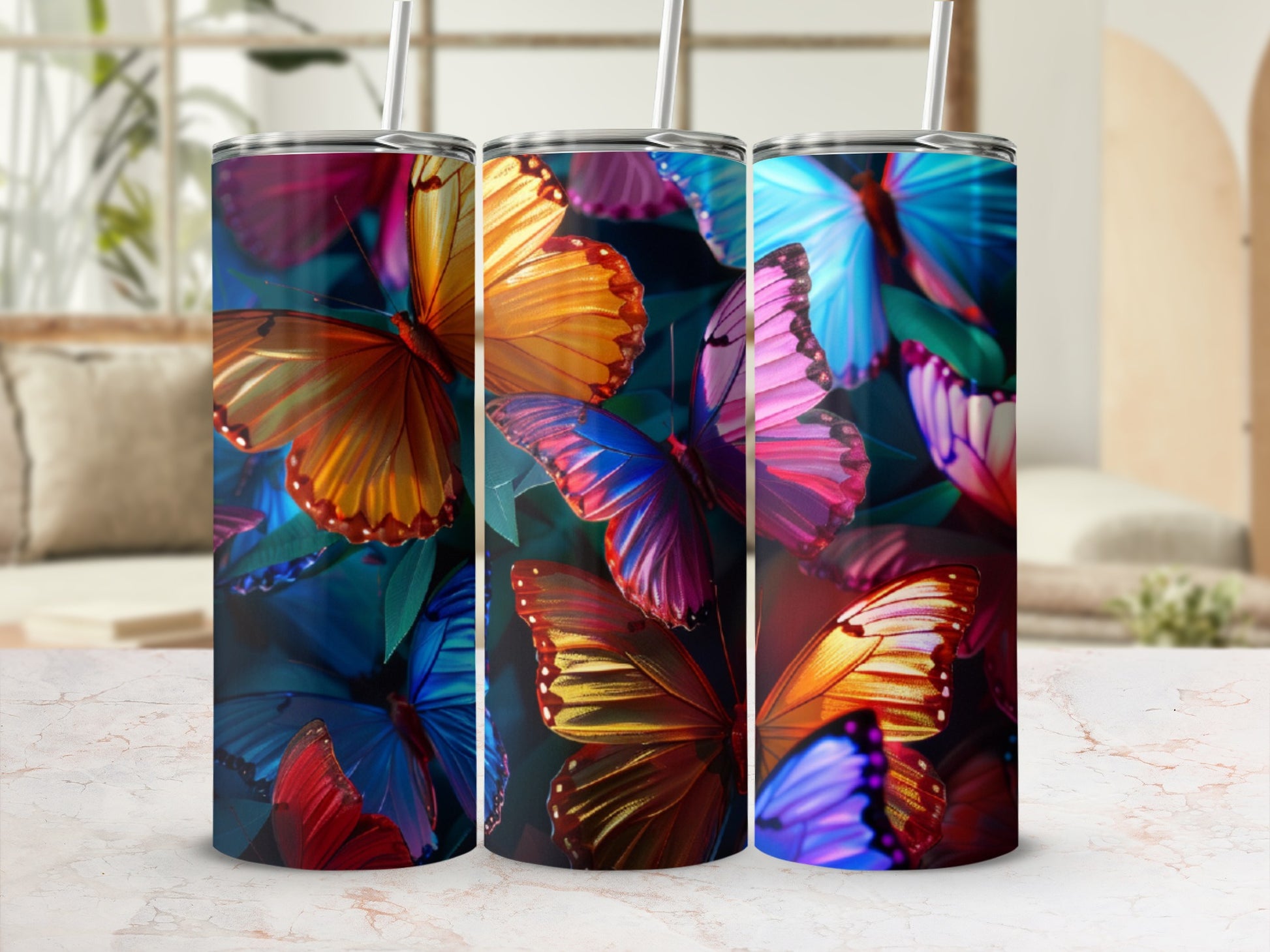 Three tumblers with colorful butterfly designs sit on a table.