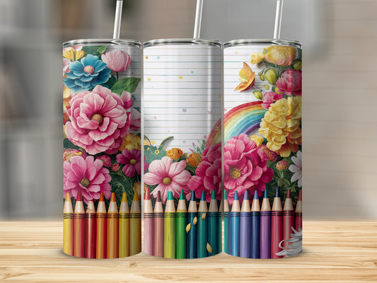Three tumblers with floral and rainbow designs, surrounded by colored pencils.