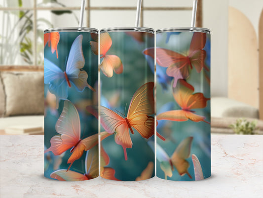 Three tumblers with colorful butterfly designs on a marble countertop.