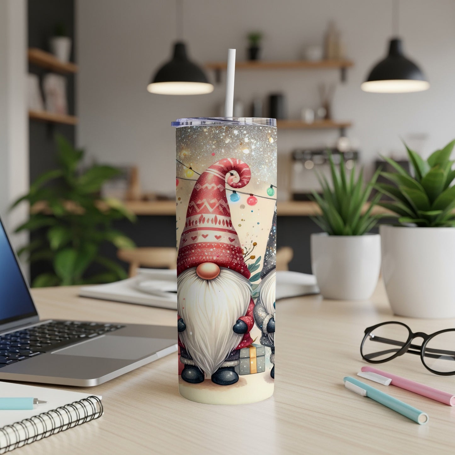 Two gnomes in festive hats hold a gift on a sparkly tumbler.