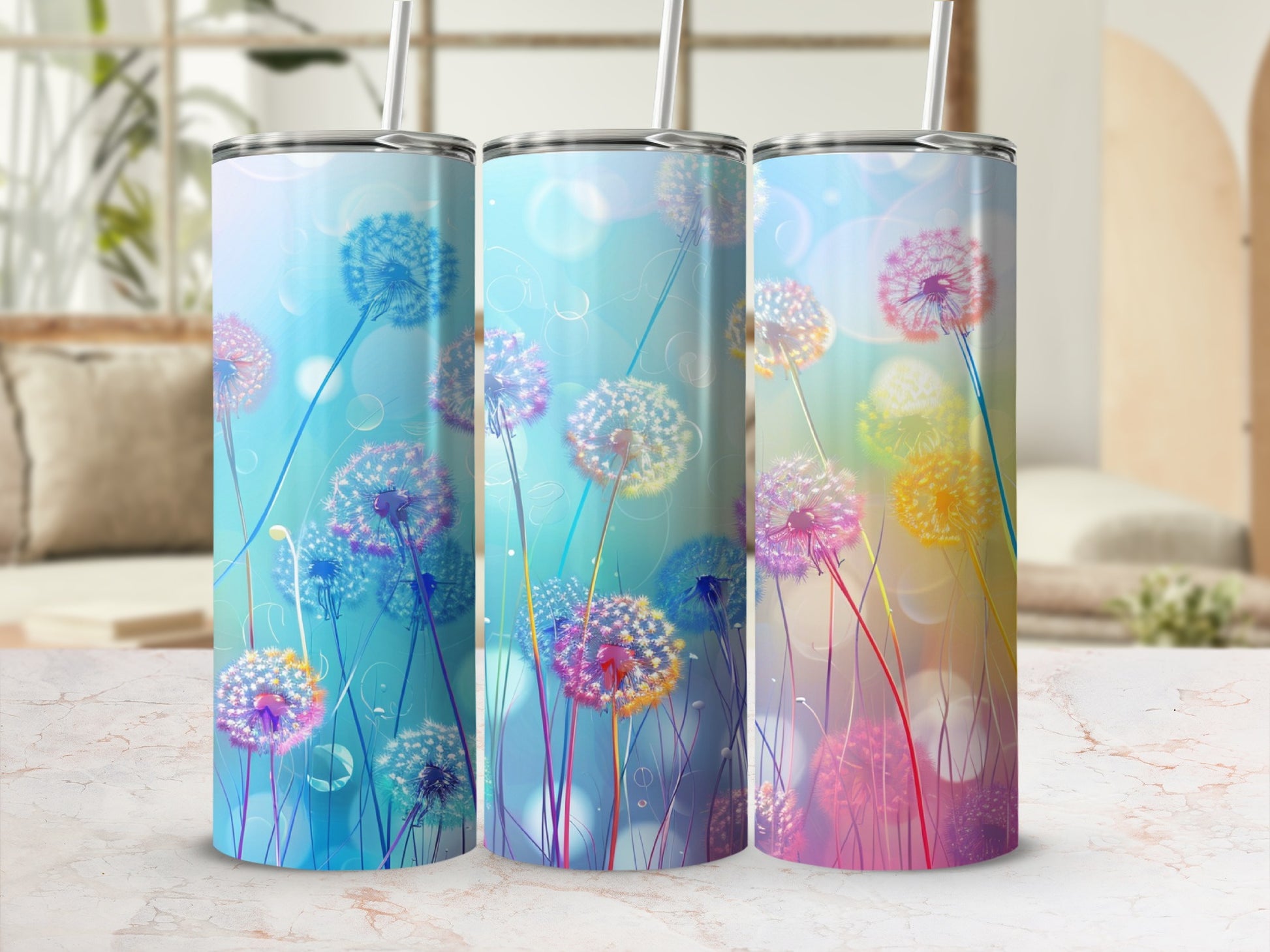 Three tumblers with dandelion designs in blue, pink, and yellow against a bokeh background.