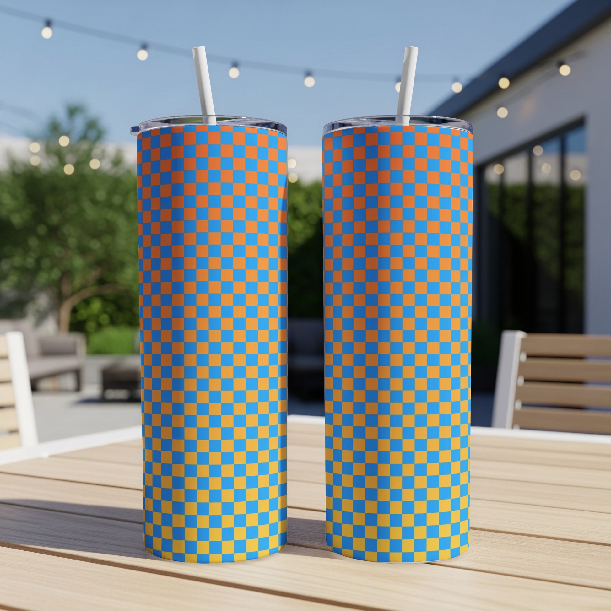 Two tall tumblers with an orange and blue checkered pattern stand on a wooden table.