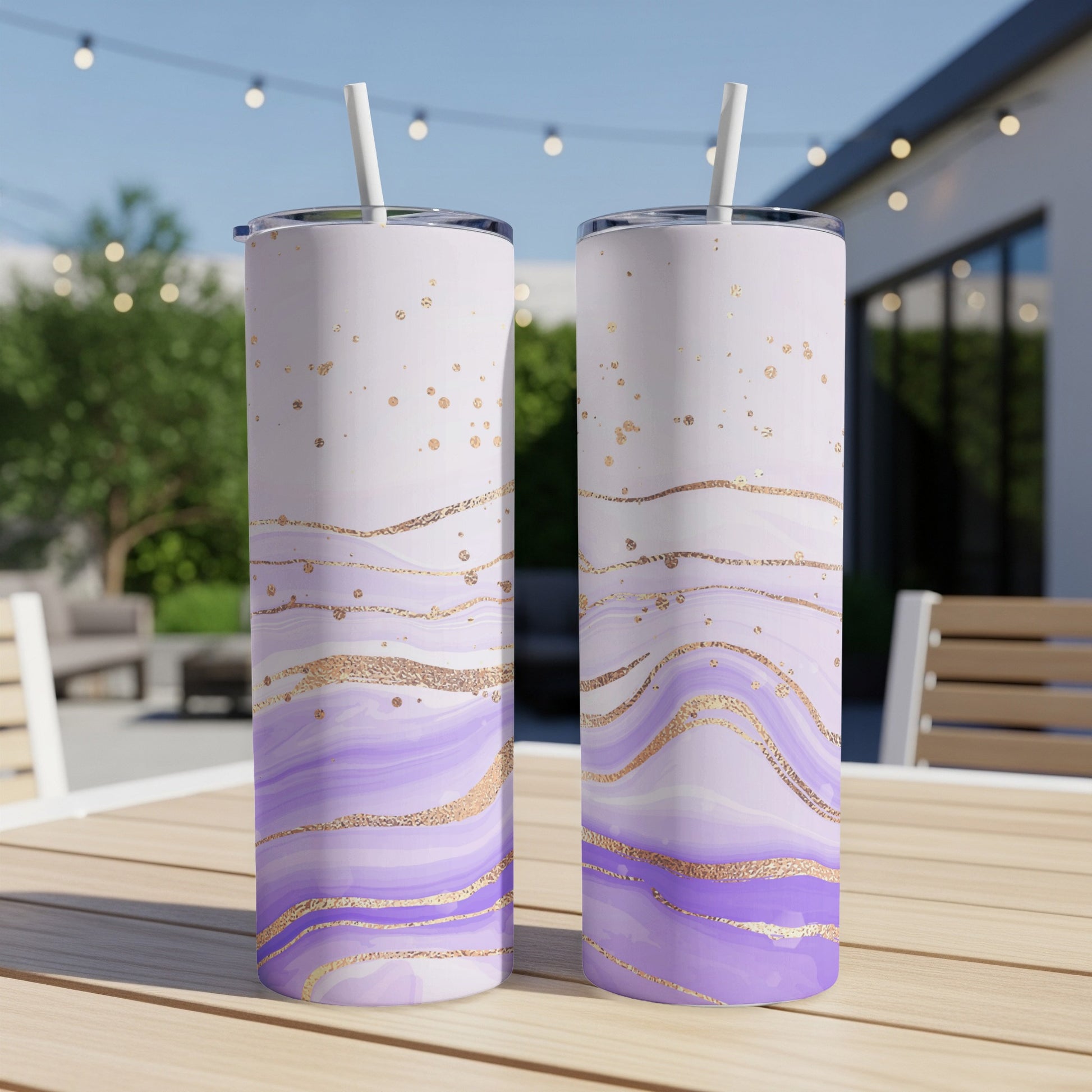 Two tall purple and gold marbled tumblers with straws on a table.