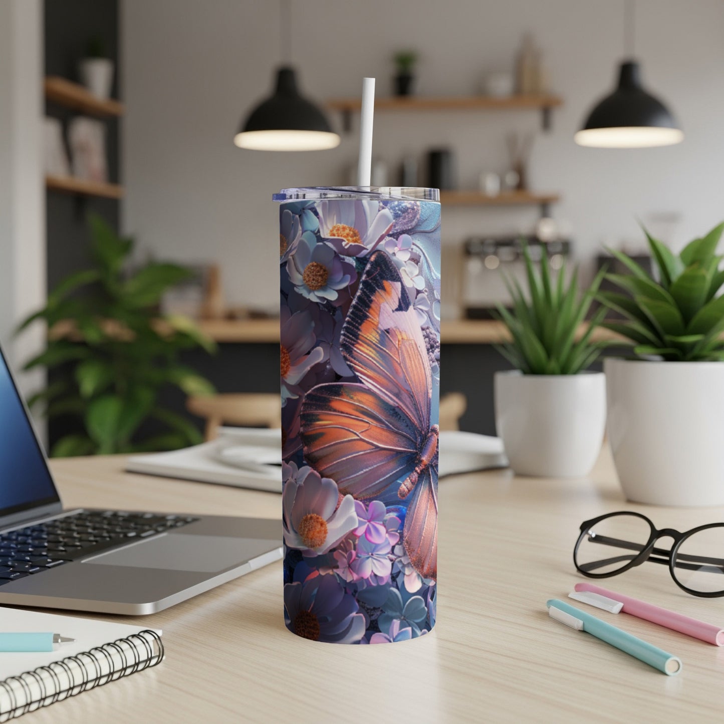 Tumbler with butterfly and floral design on a desk.