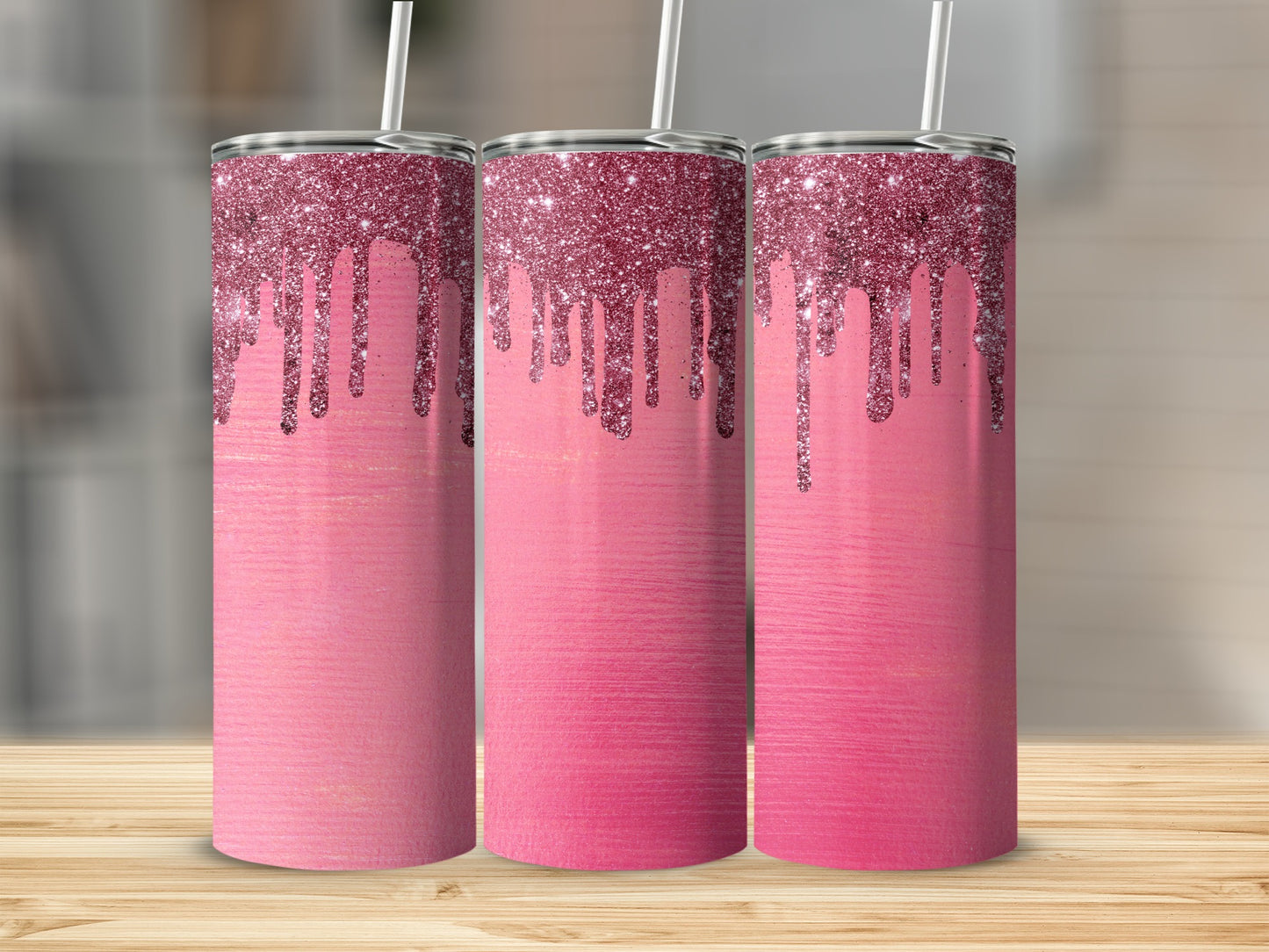 Three pink tumblers with dripping glitter on a wooden surface.
