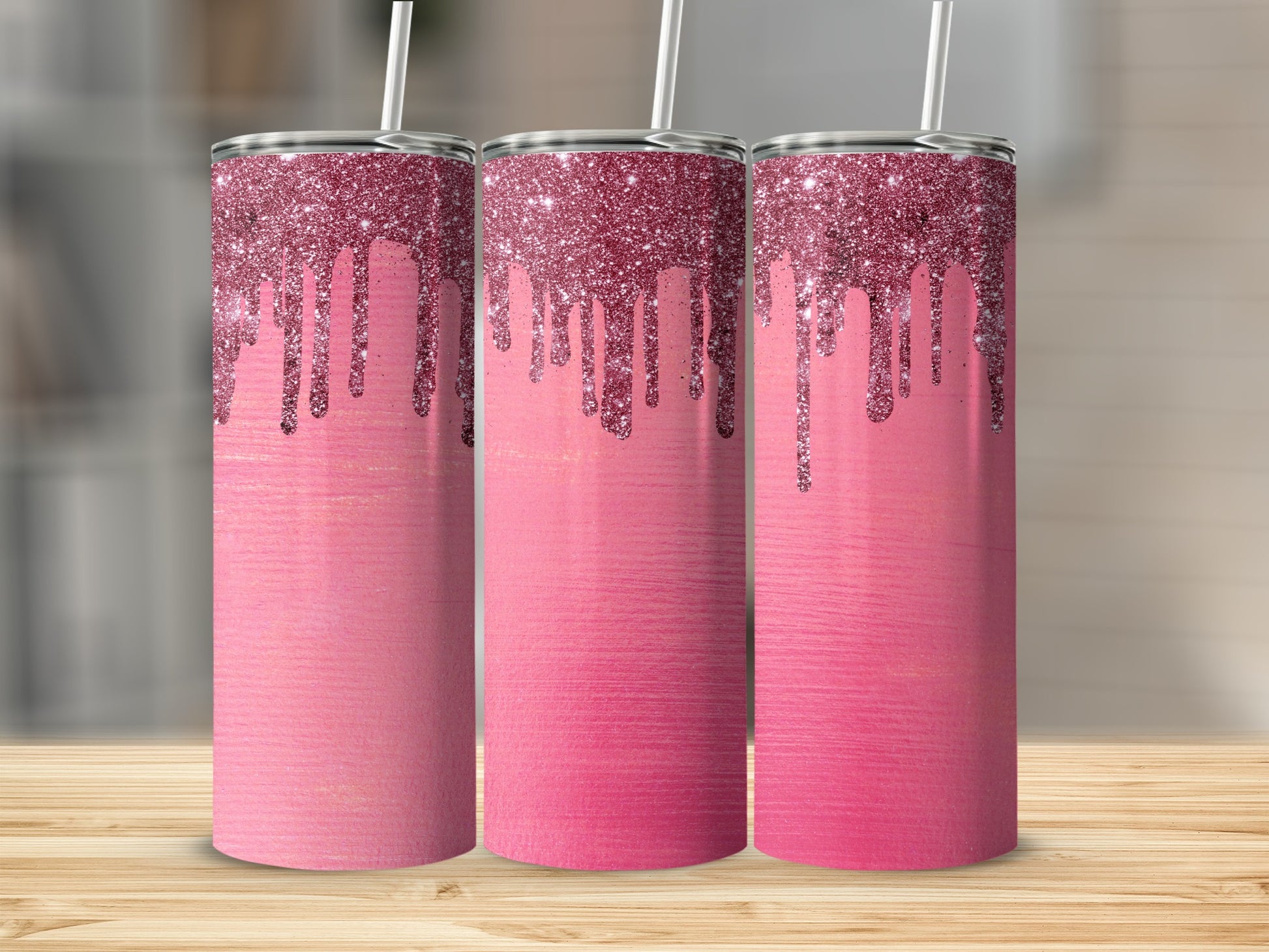 Three pink tumblers with dripping glitter on a wooden surface.