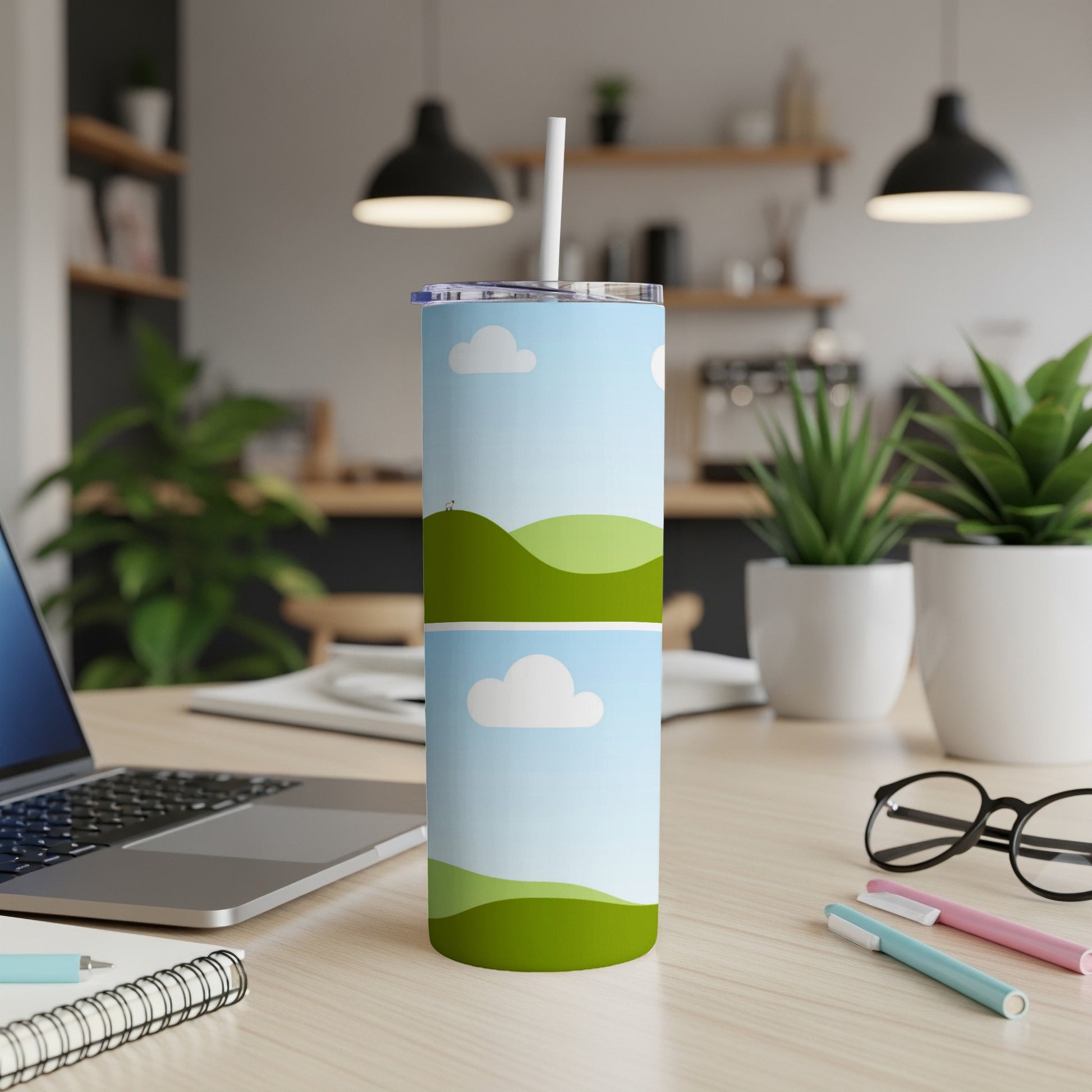 Tall tumbler with a whimsical landscape and cloud design, featuring a straw.