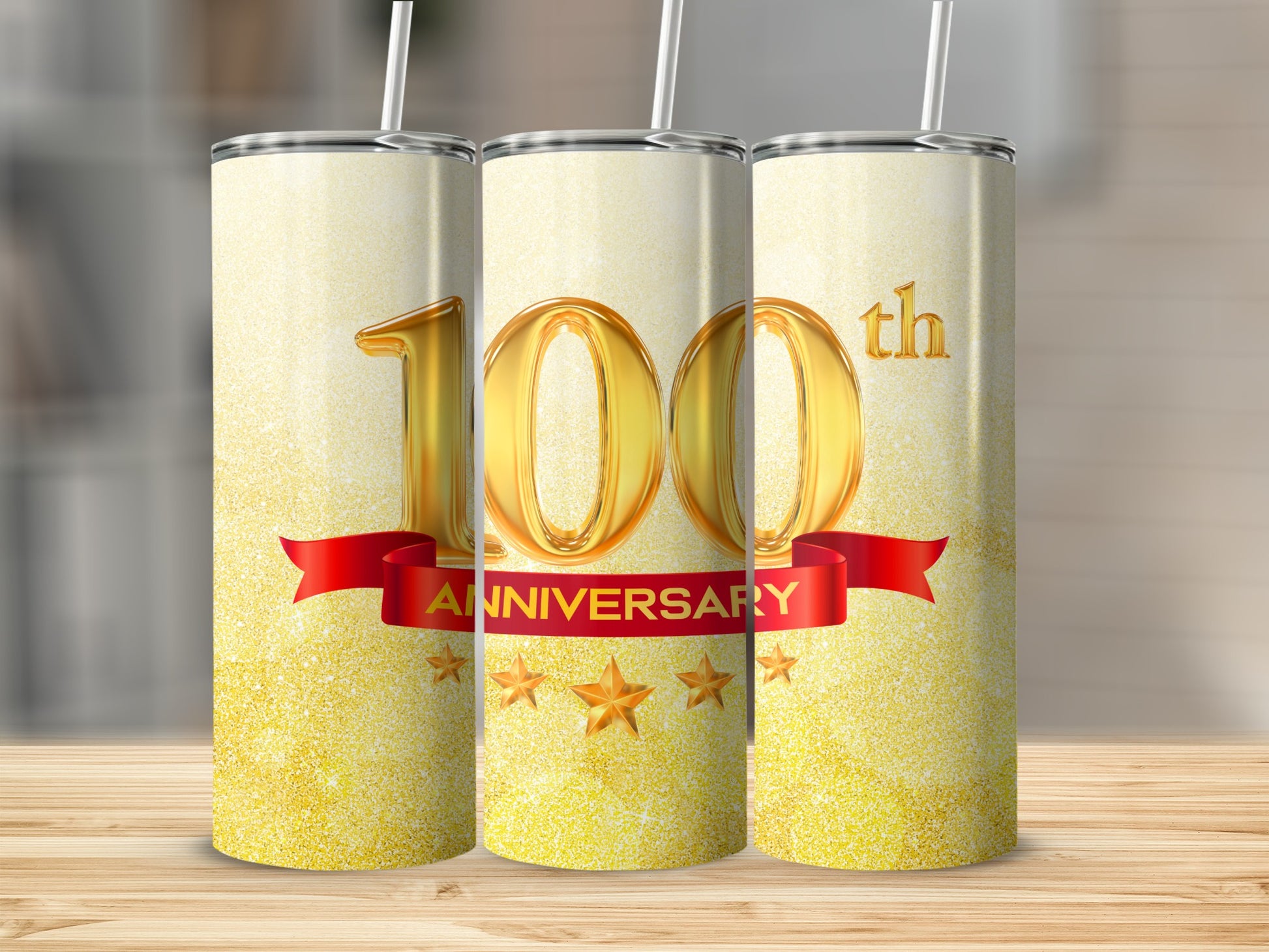 "100th Anniversary" text on a sparkling gold tumbler with a red ribbon and stars.