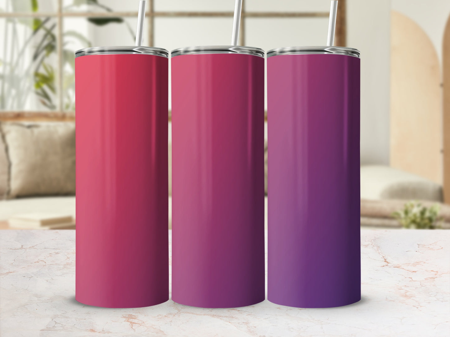 Three gradient colored tumblers with straws on a marble surface.