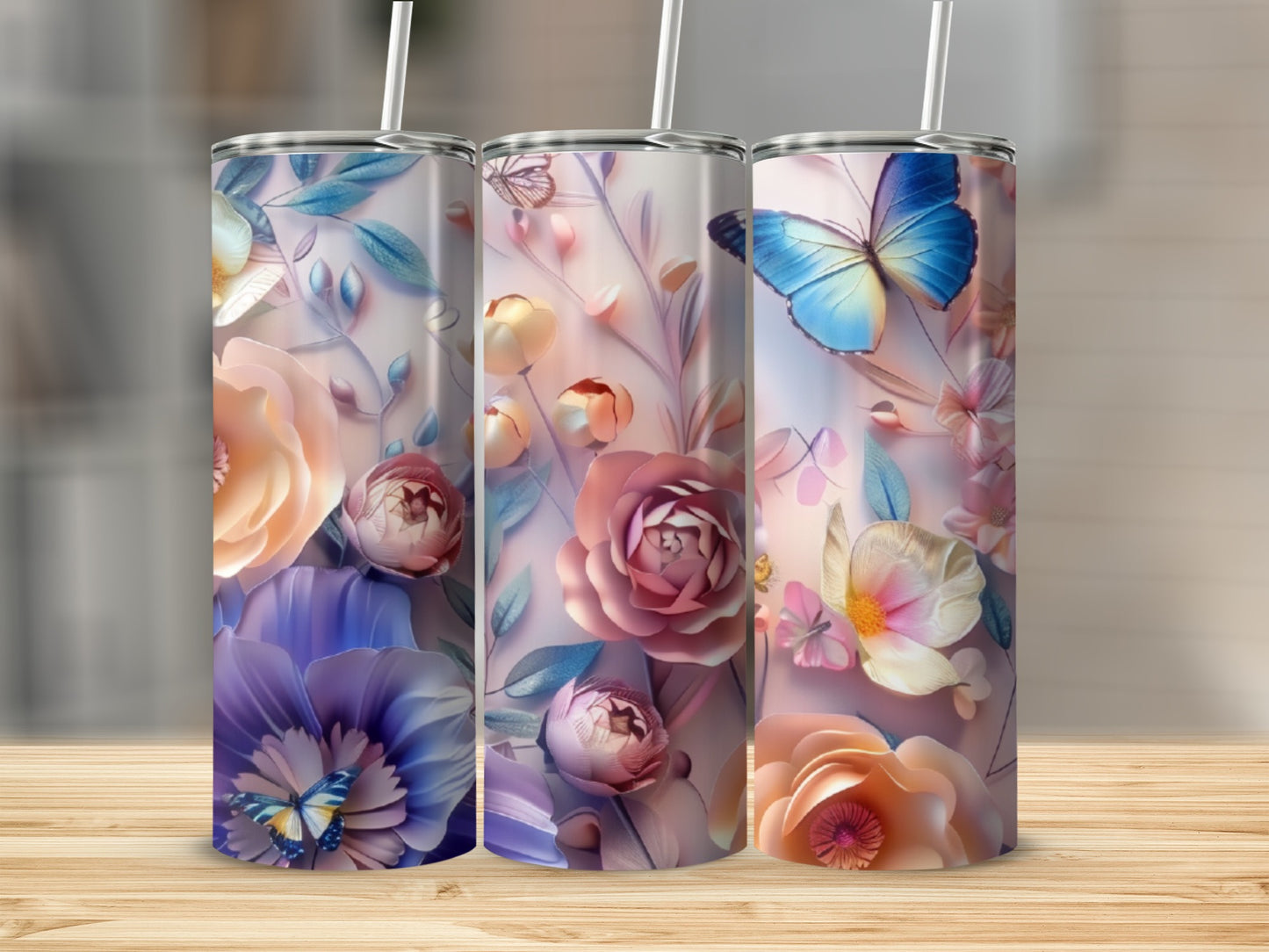 Three tumblers with floral and butterfly designs on a wooden surface.
