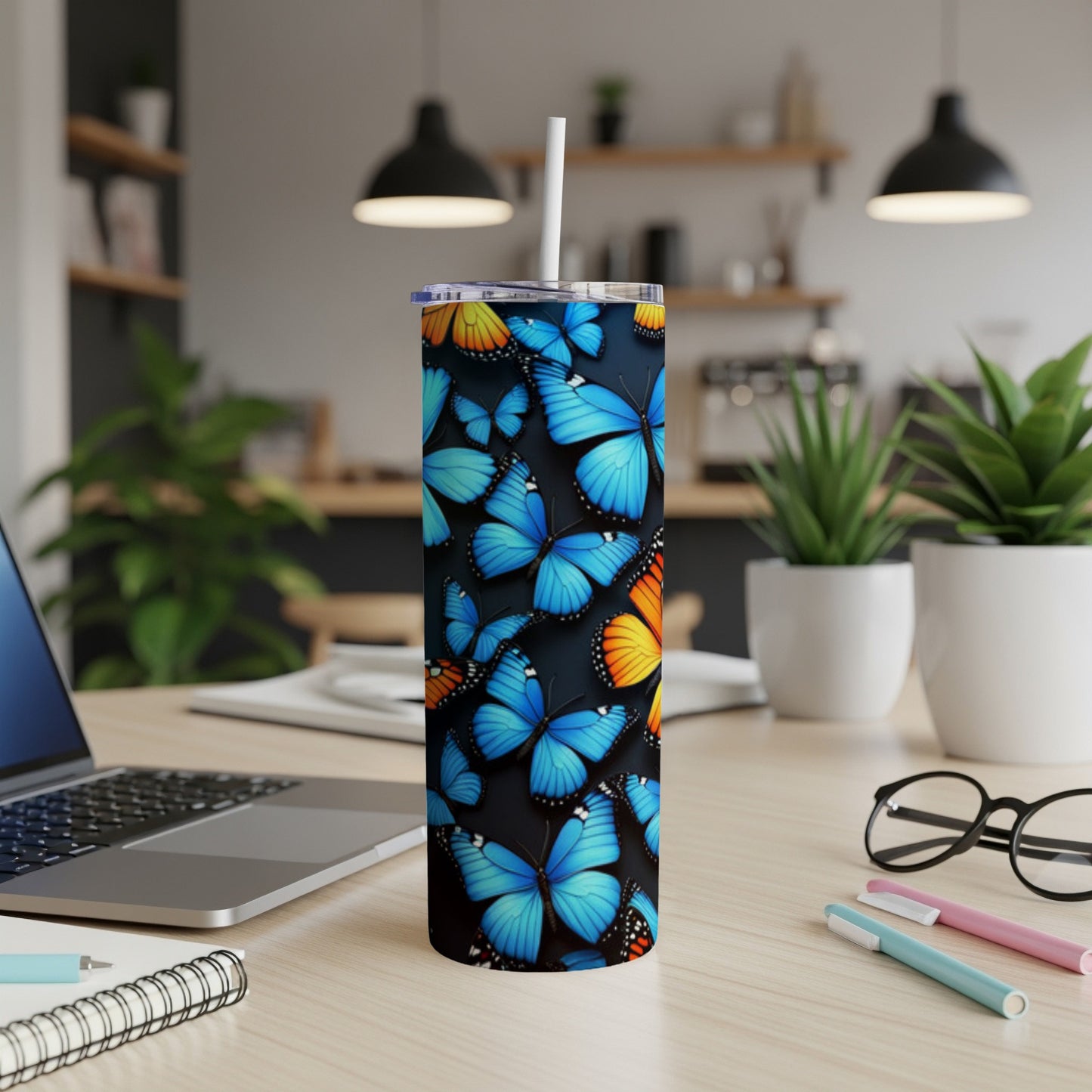 Blue and orange butterflies adorn a black stainless steel tumbler on a desk.