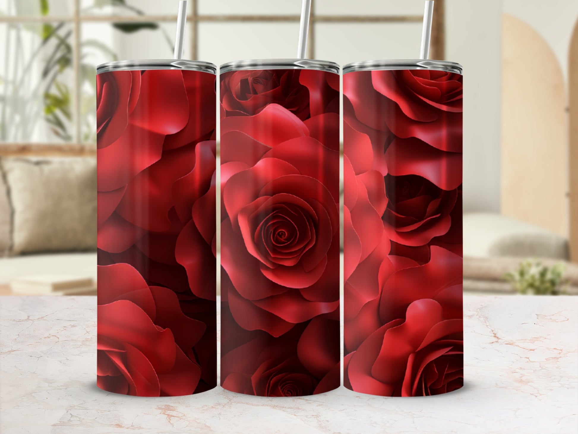 Three red rose pattern tumblers with straws on a marble surface.