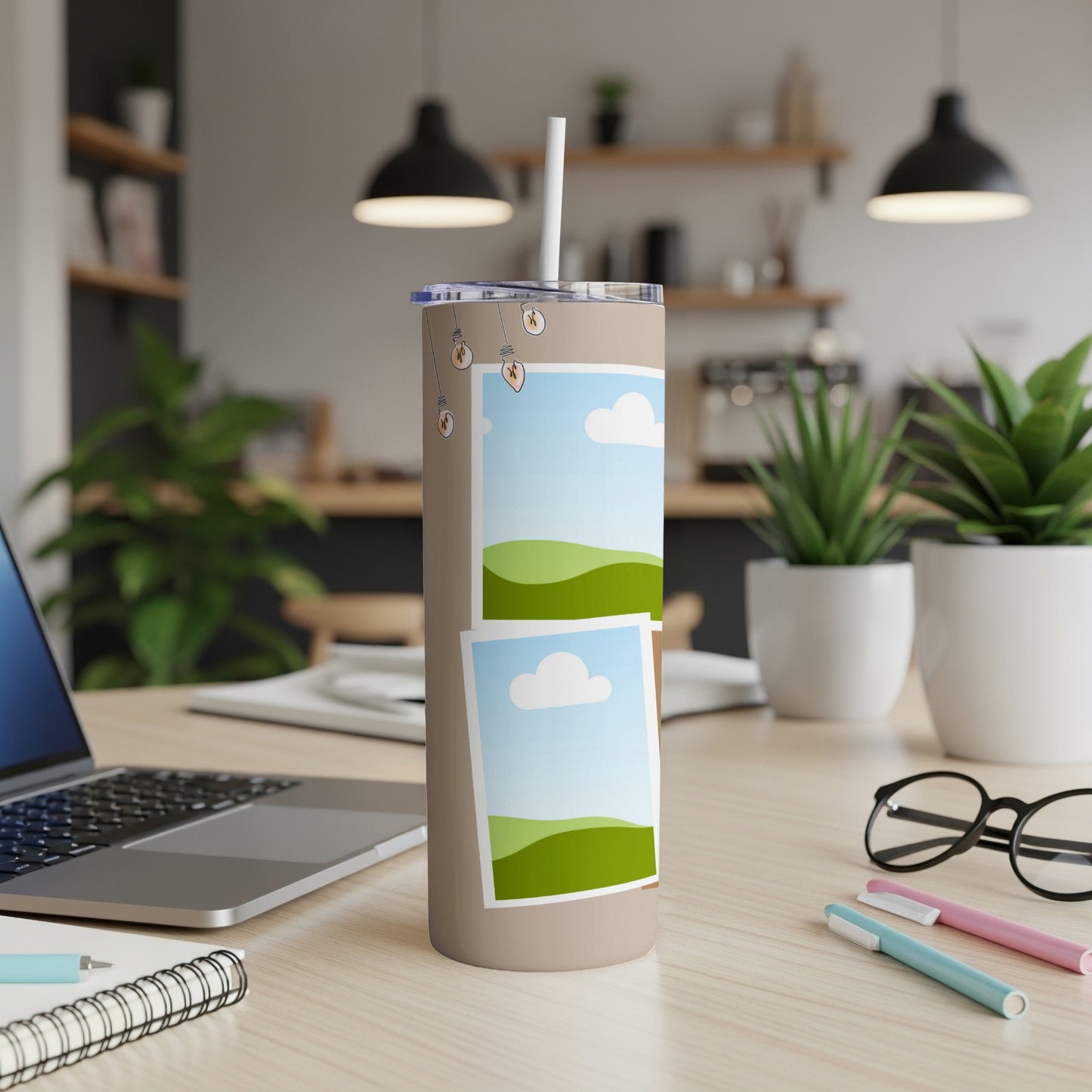 Tan tumbler with straw, featuring two framed landscape images and lightbulb graphics.