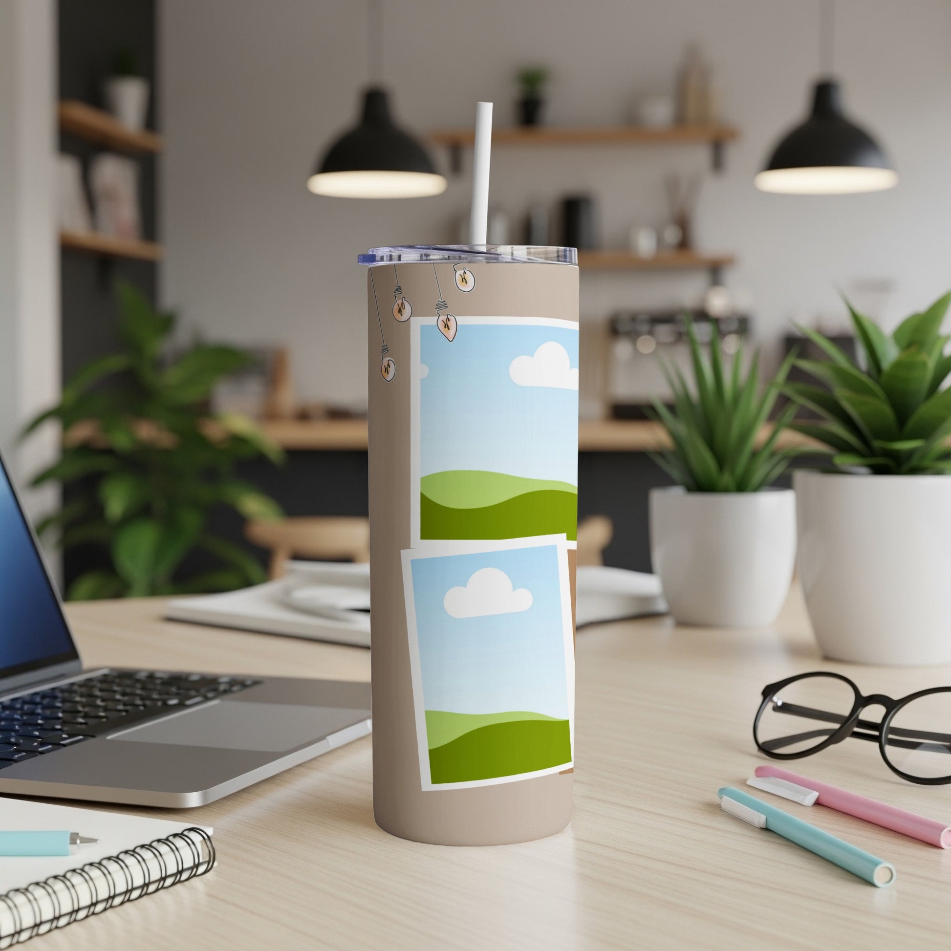 Tan tumbler with straw, featuring two framed landscape images and lightbulb graphics.