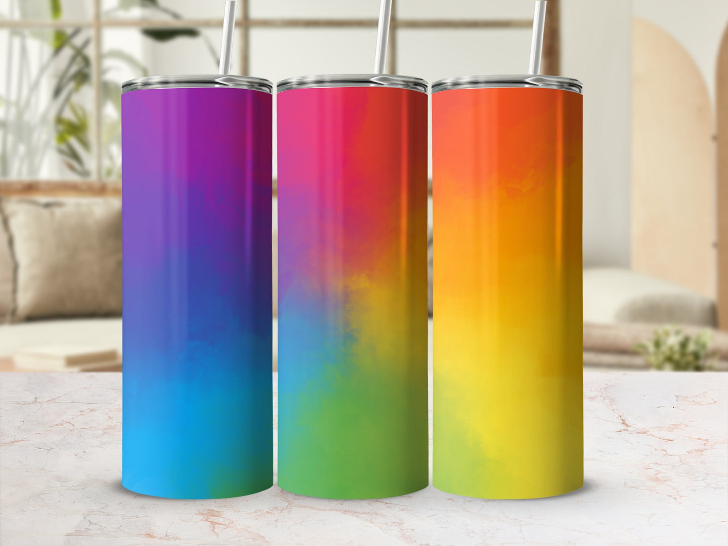Three tumblers with rainbow gradient designs and straws, displayed on a surface.