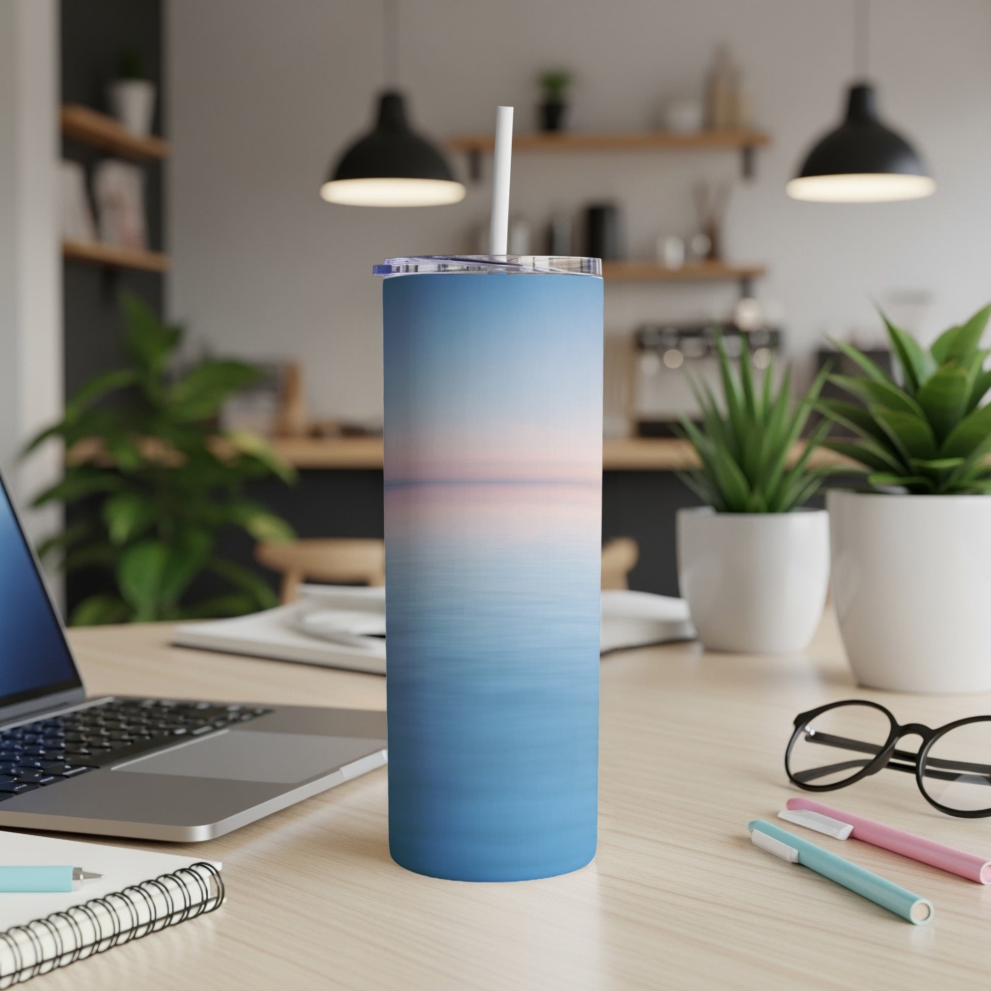 Blue gradient sunset scene on a stainless steel tumbler with straw.