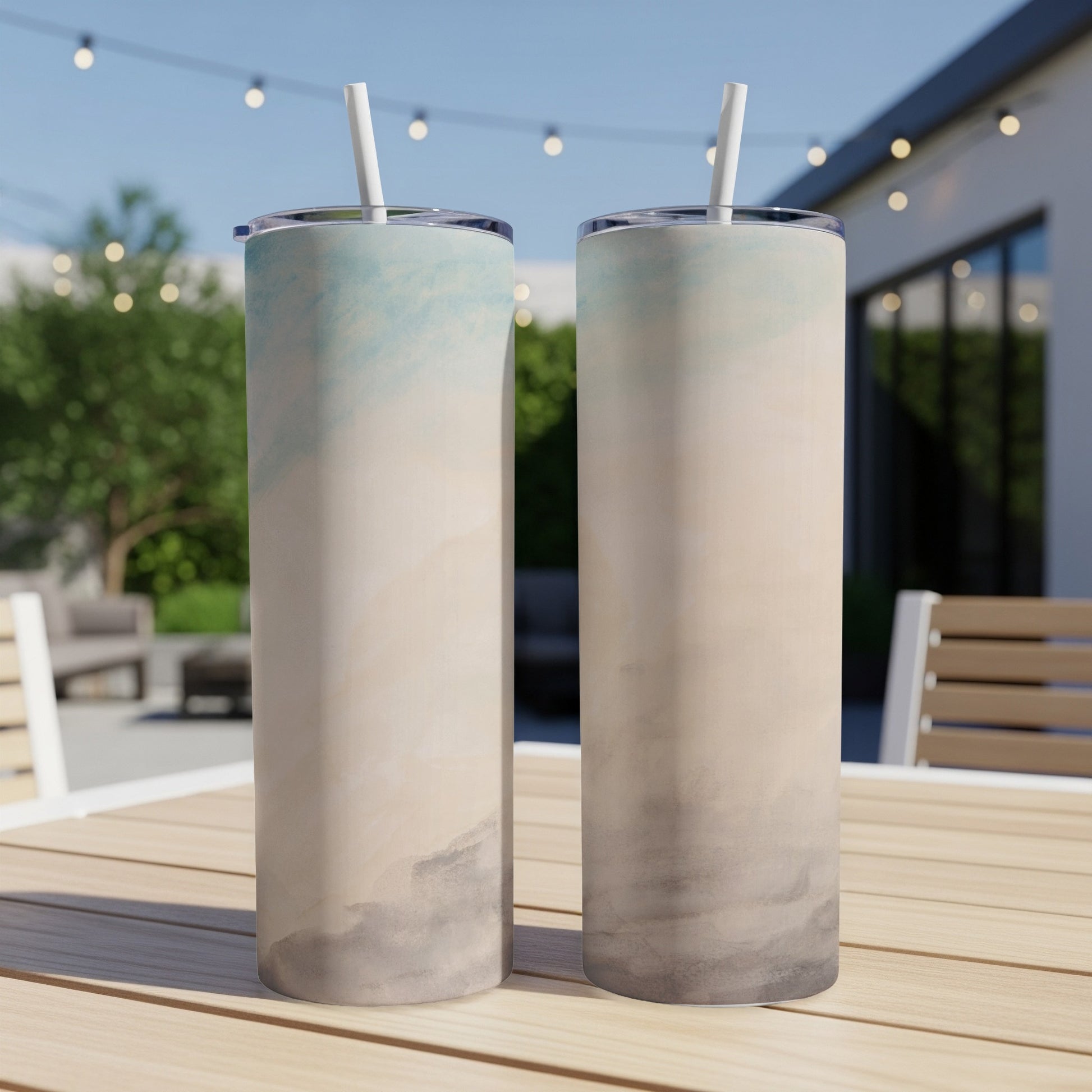 Two tall, slim tumblers with a watercolor-style gradient design sit on a wooden table.