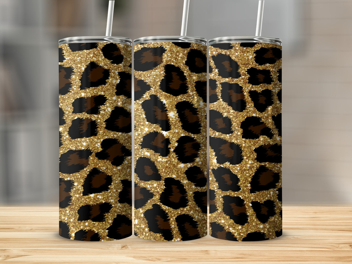 Three tumblers with gold glitter and black leopard print patterns stand on a wooden surface.