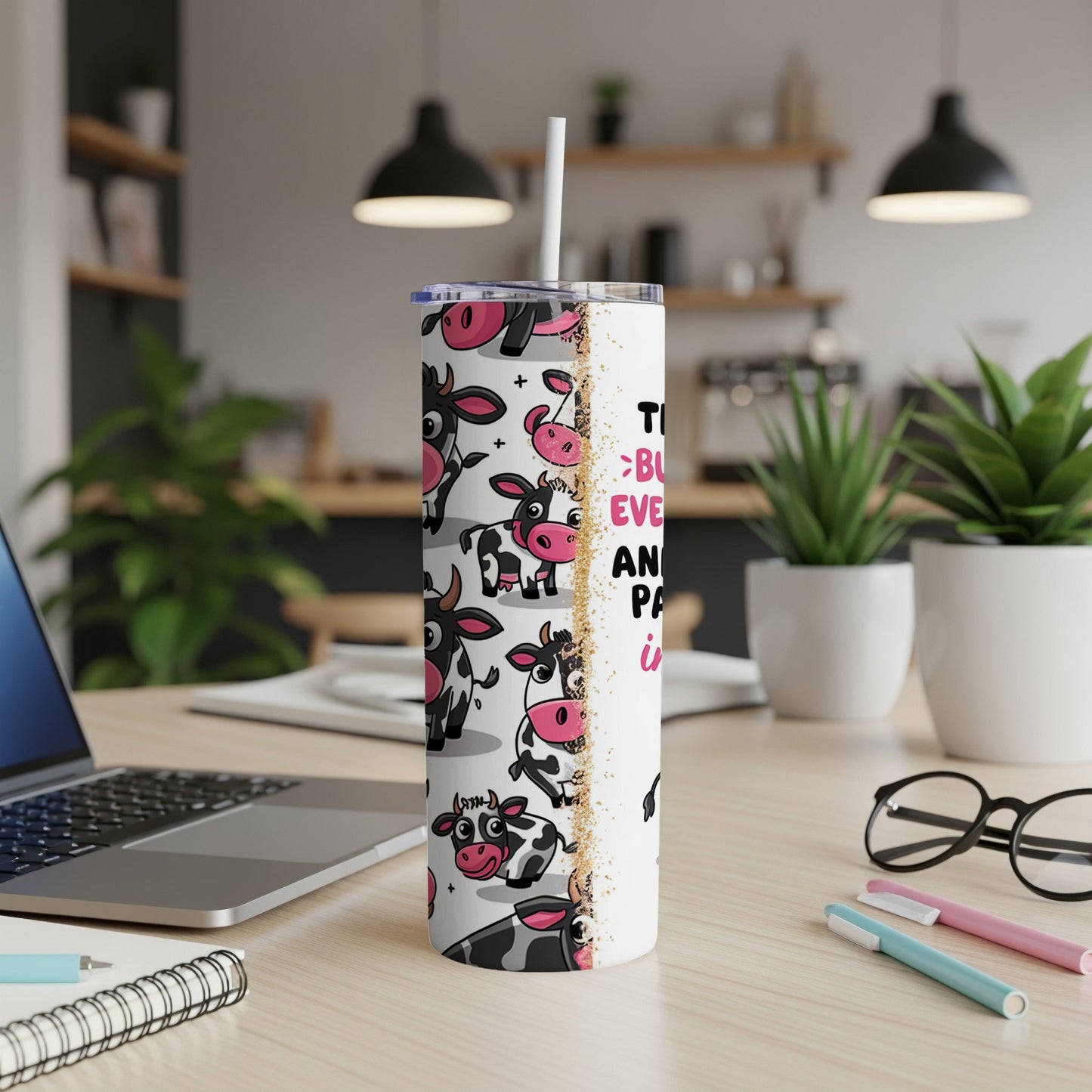Cow pattern tumbler with text on a desk.