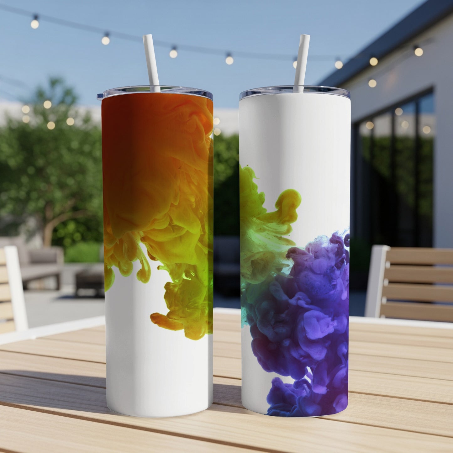 Two tumblers with colorful ink splashes on a wooden table outdoors.