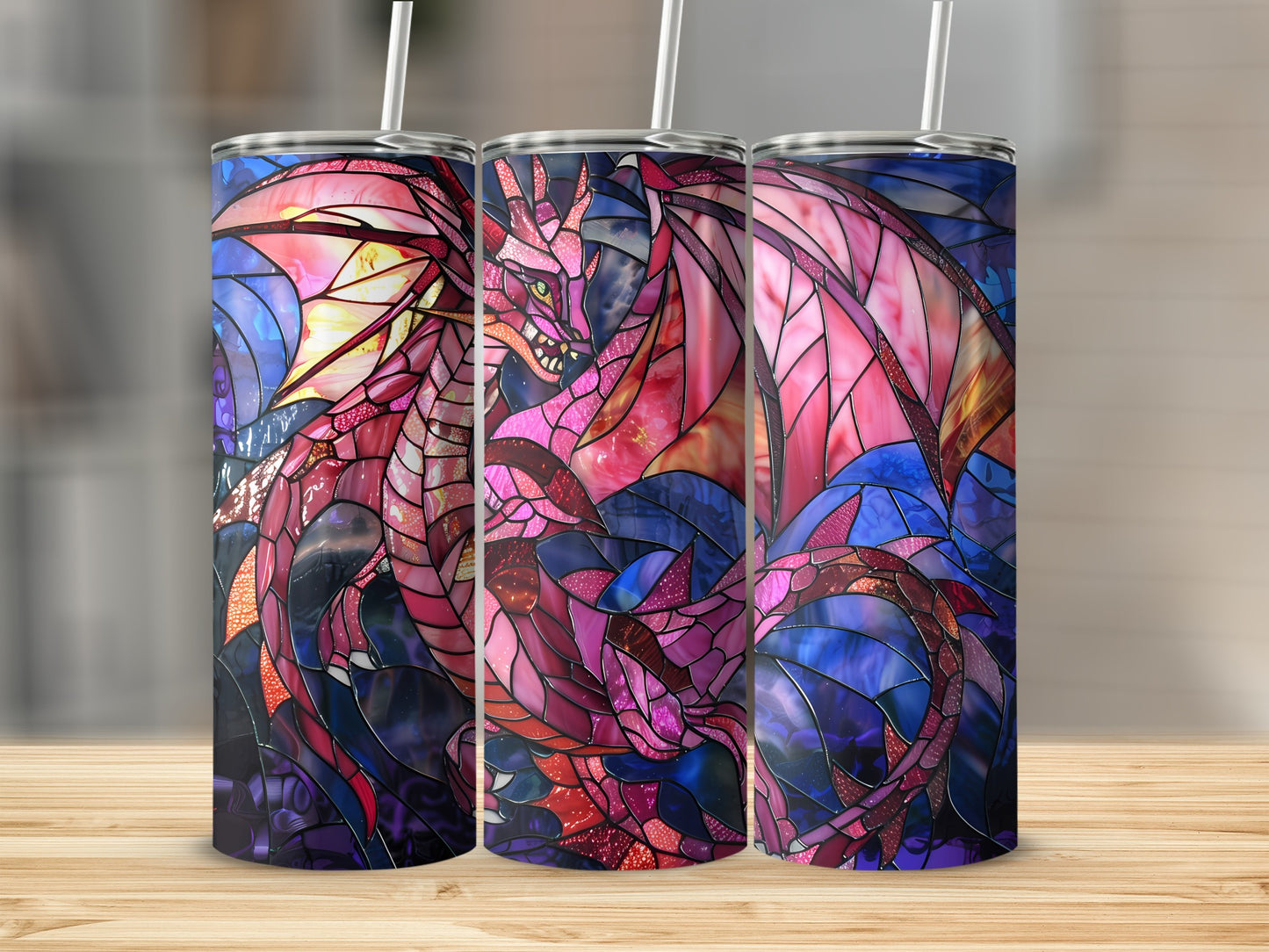 Dragon stained glass pattern on three tumblers with straws on a wooden surface.