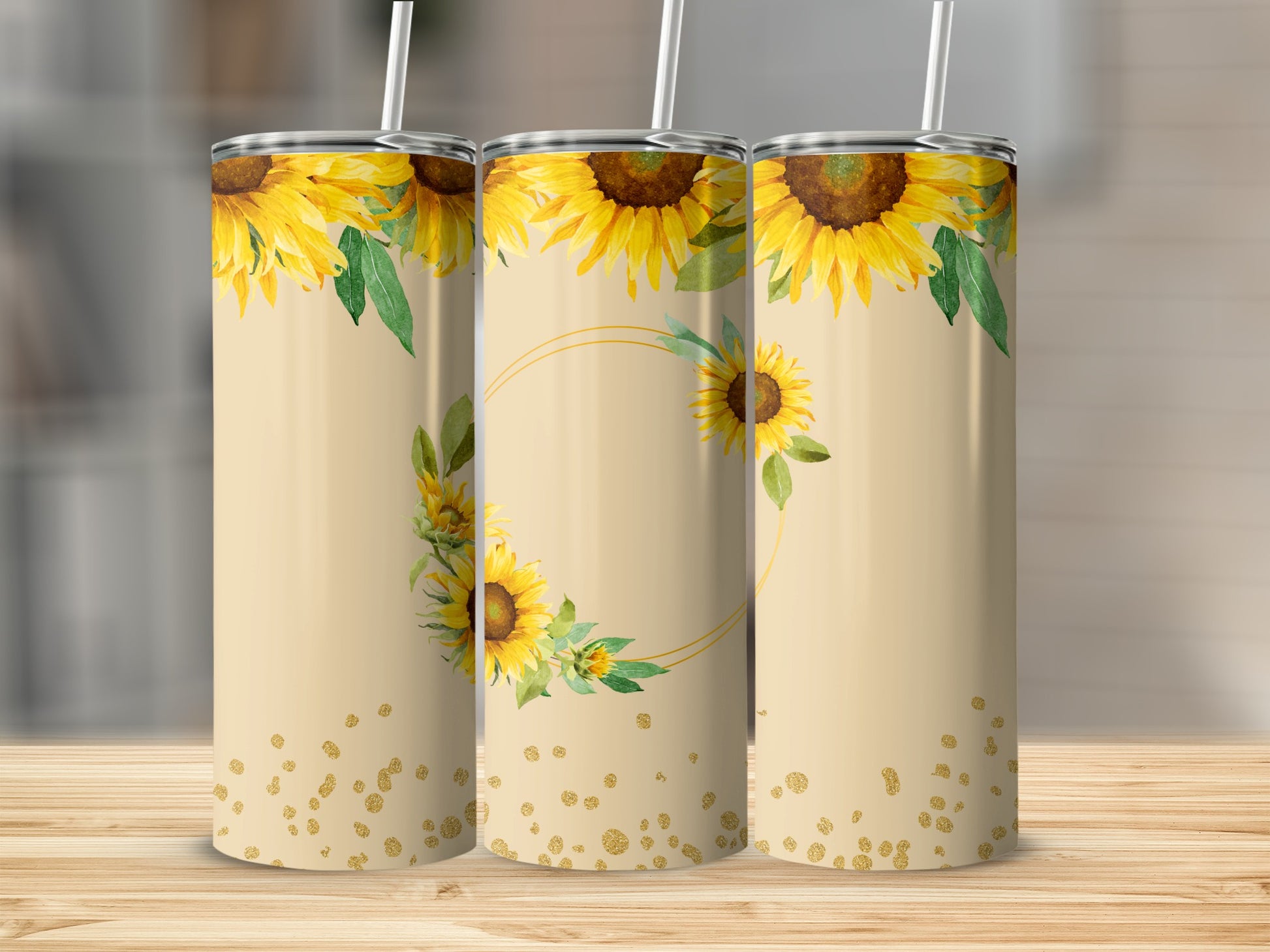 Three tall tumblers with sunflowers and gold glitter design on a wooden surface.