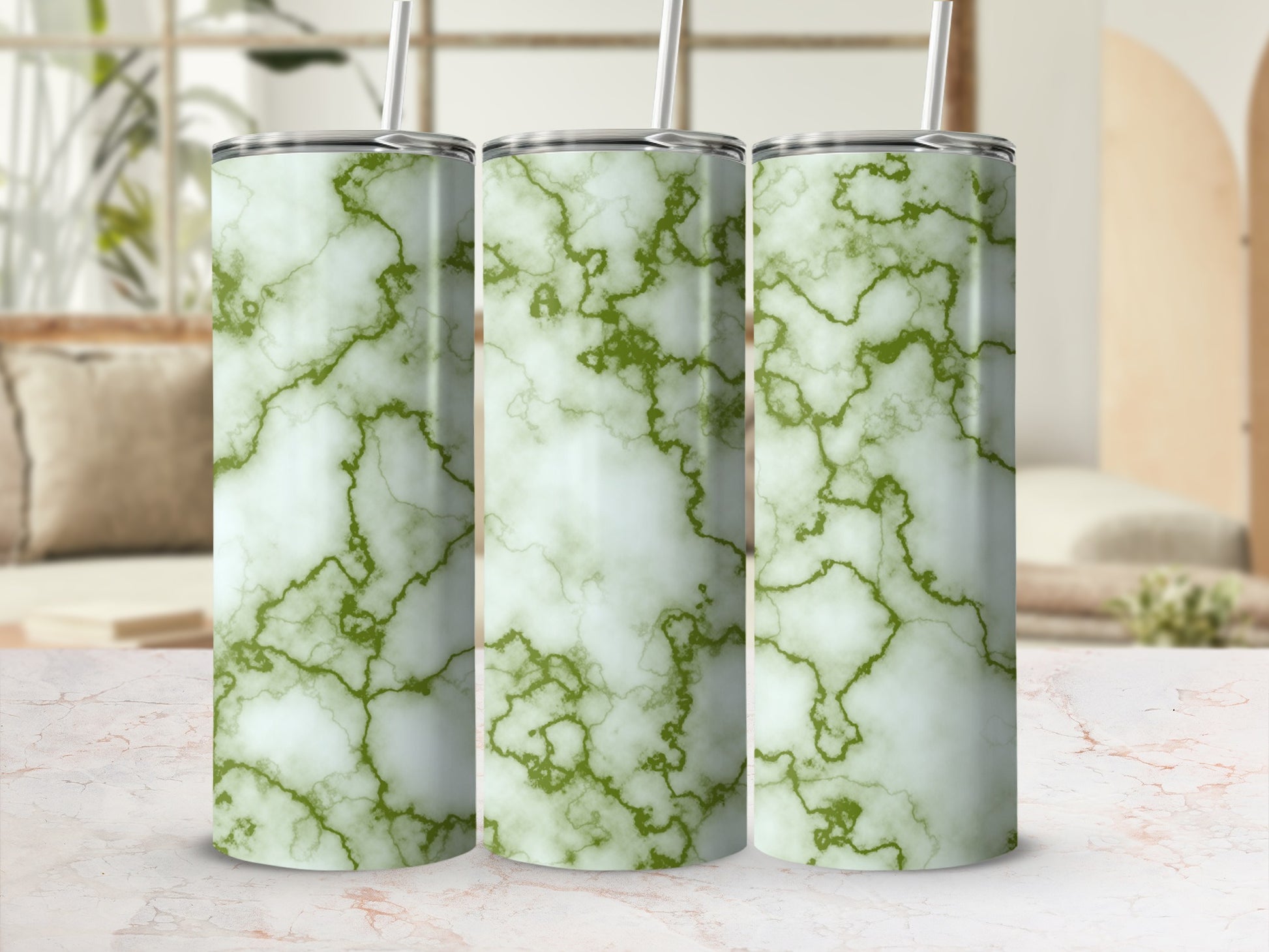 Three white and green marble pattern tumblers with straws on a marble surface.