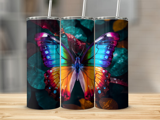 Three tumblers with vibrant butterfly wings design on a blurred floral background.