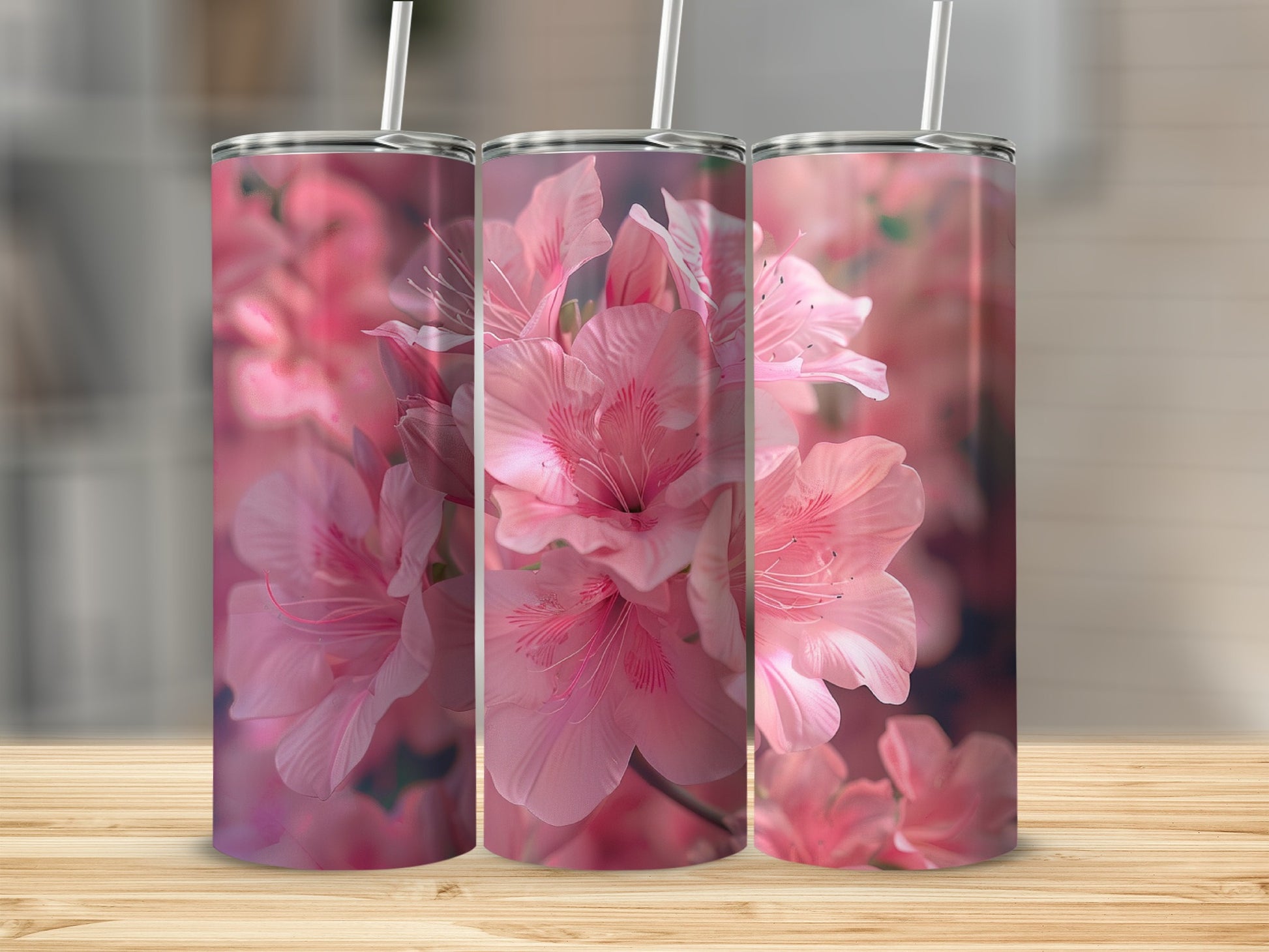 Three pink floral tumblers with straws on a wooden surface.