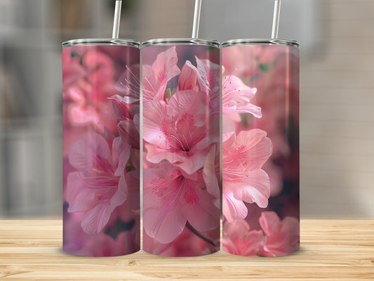 Three pink floral tumblers with straws on a wooden surface.