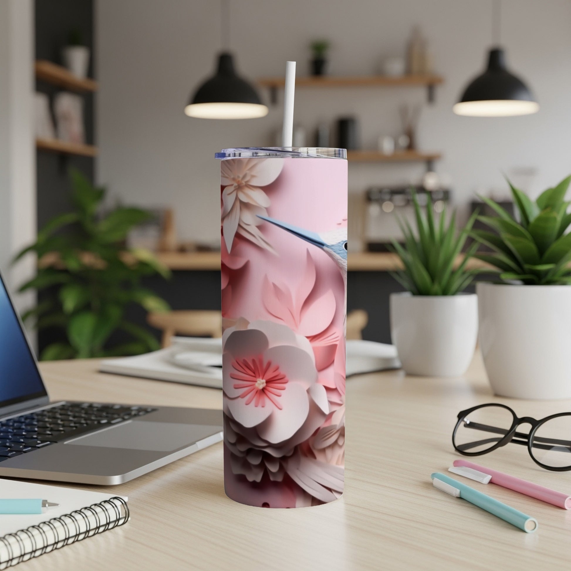 Pink floral patterned tumbler with a straw, on a desk.