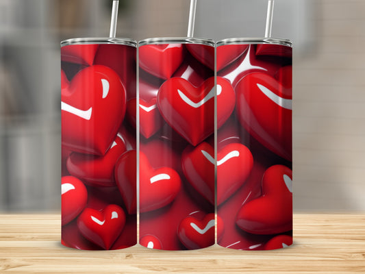 Three red heart-patterned tumblers on a wooden surface.