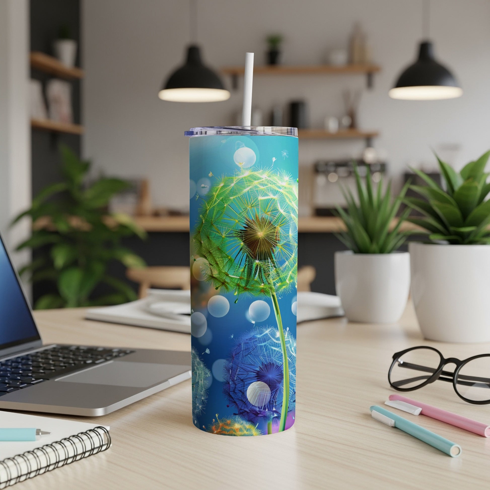 Blue tumbler with dandelion design and straw on a desk.