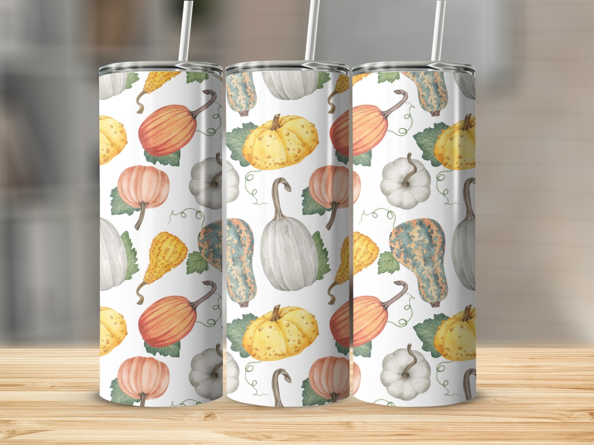 Pumpkin and gourd pattern on three white tumblers with straws.