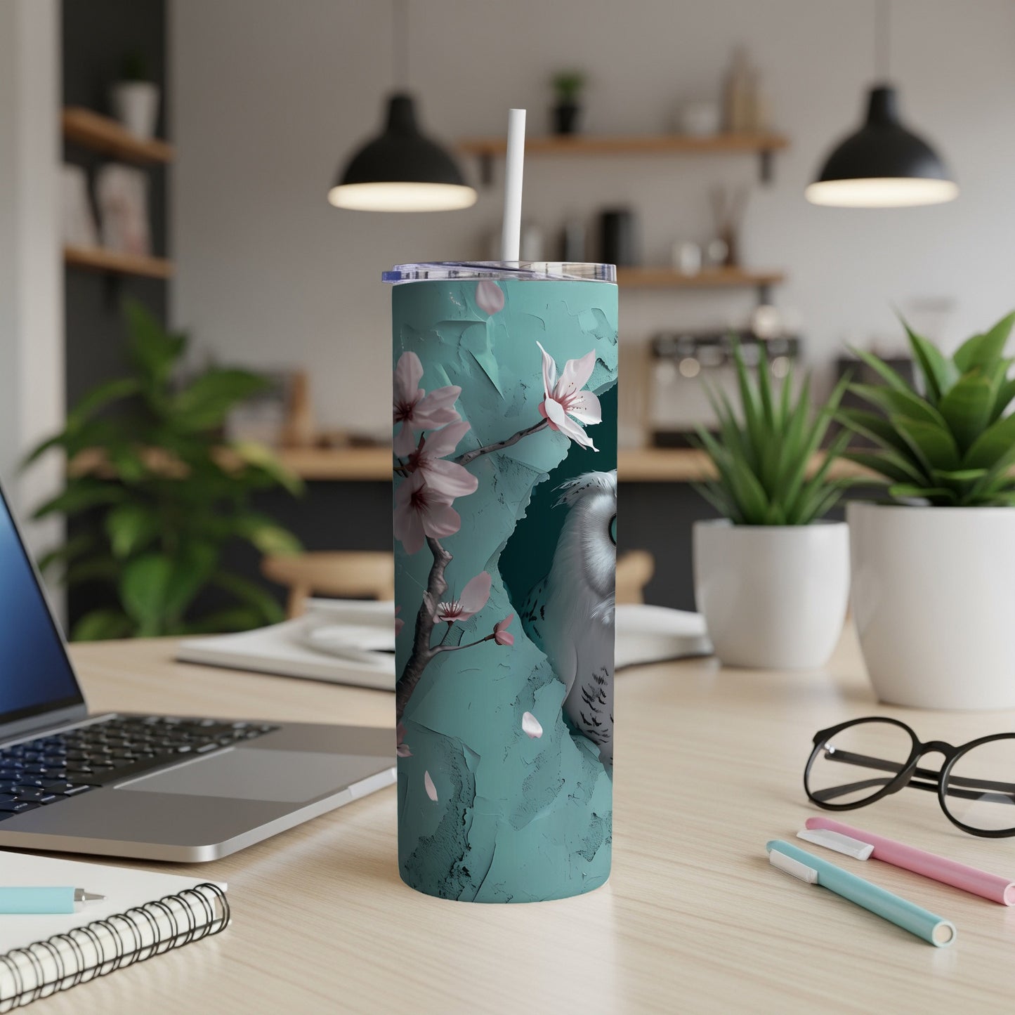 White owl on teal background with cherry blossoms, on a desk.
