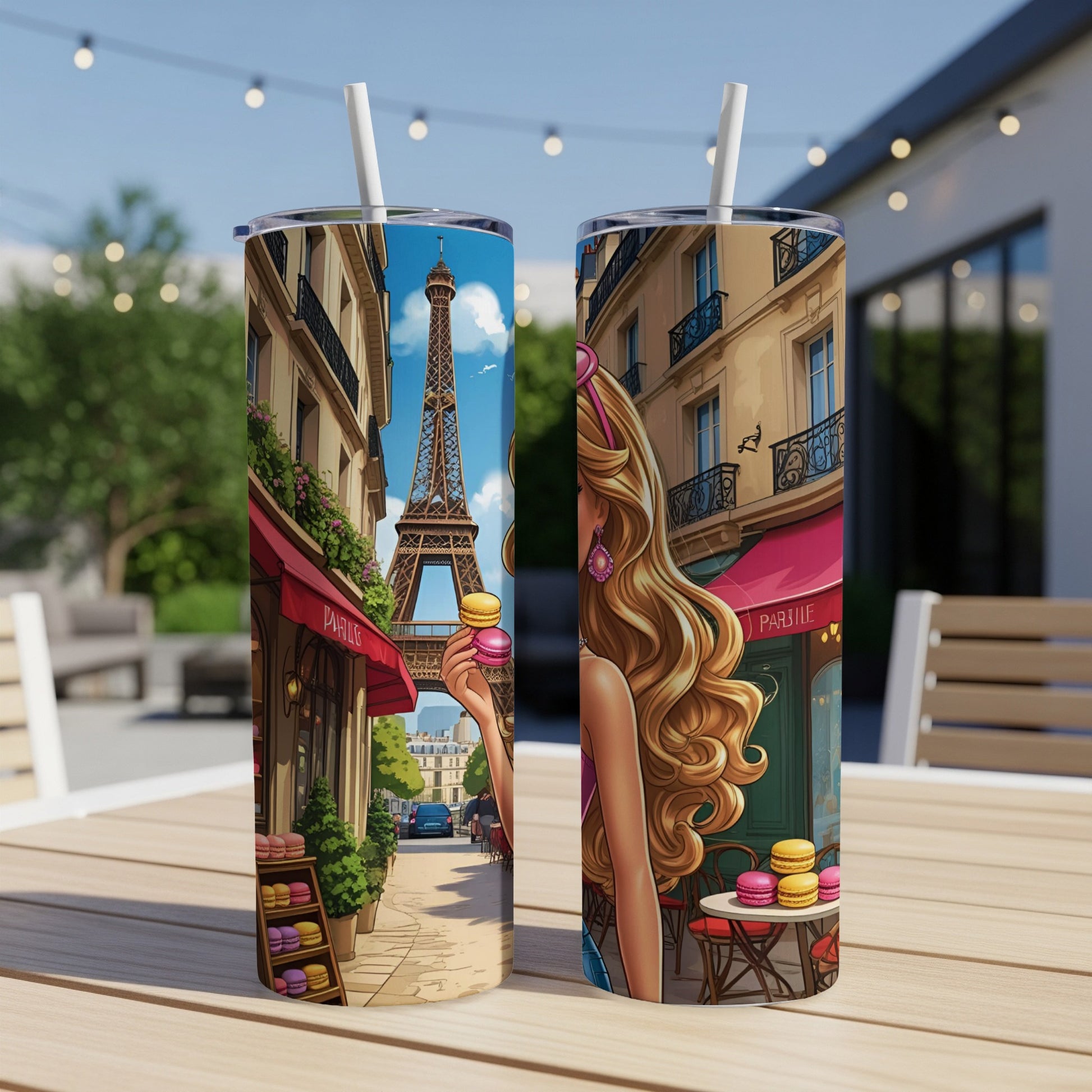 Two tumblers with Eiffel Tower and macaron artwork on a table.