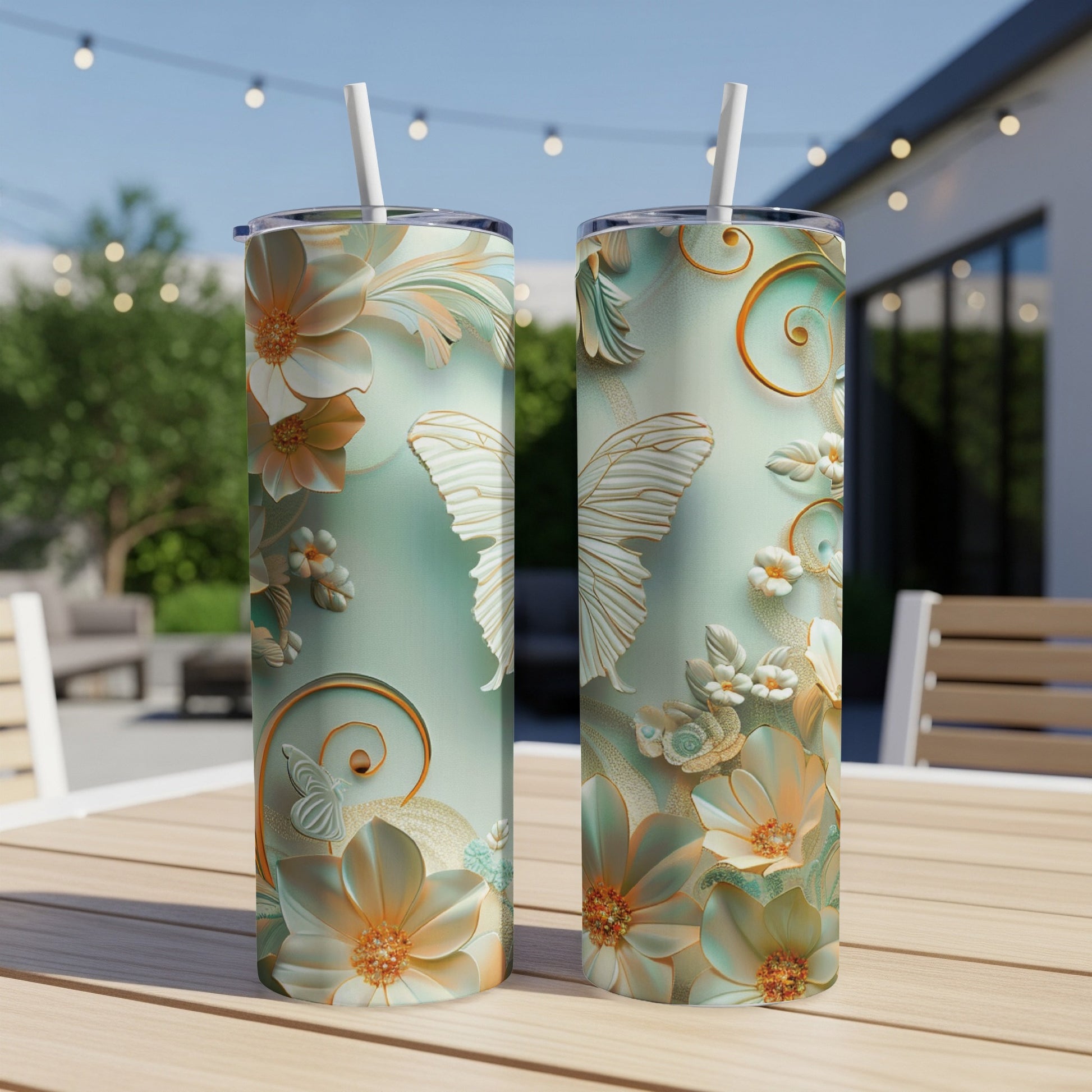 Two tall tumblers with floral and butterfly designs on a table.