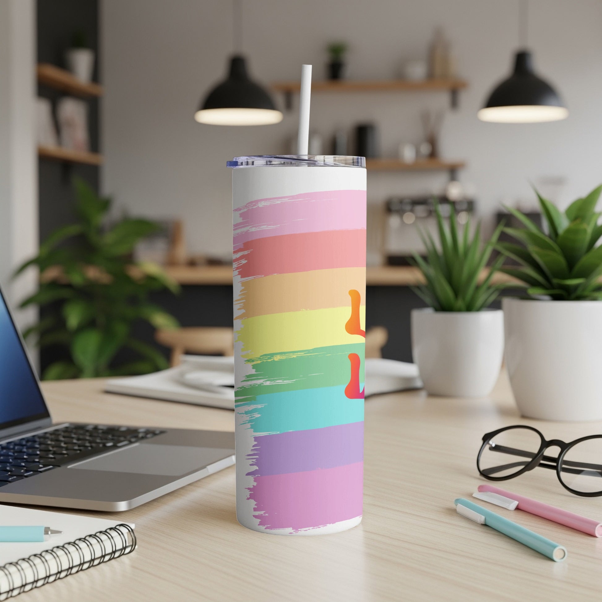 Rainbow striped tumbler with a white straw on a desk.